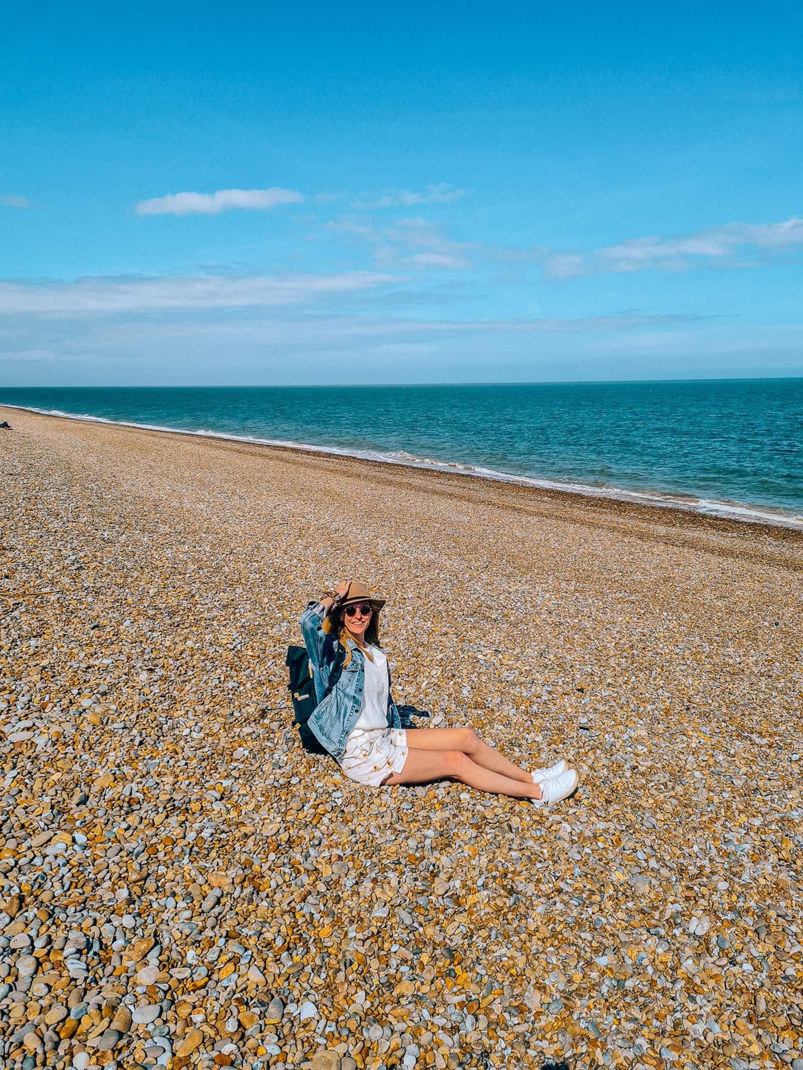 girl sitting on a pebble beach in the sun