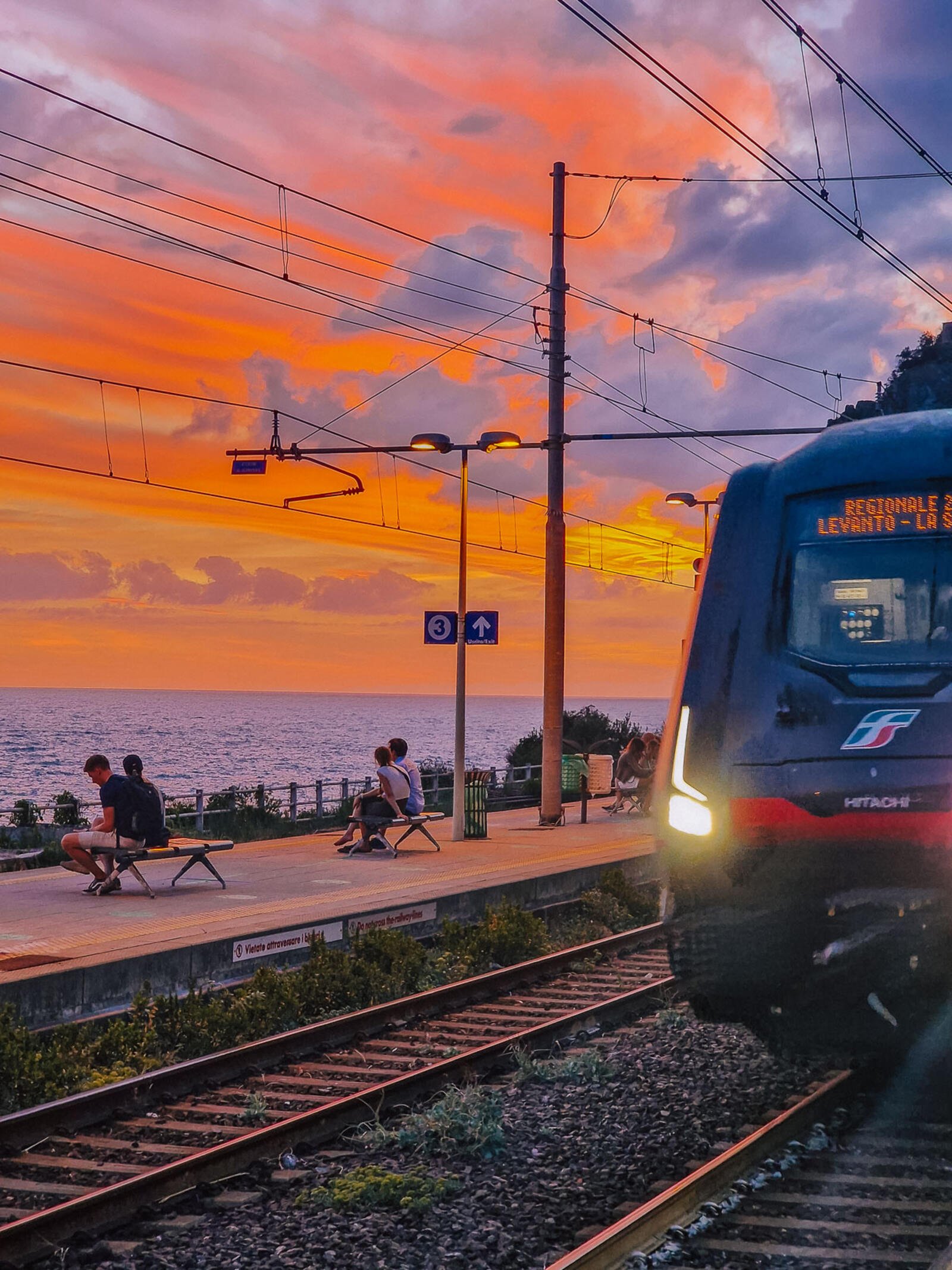 a rain coming into a station by the sea at sunset in italy's cinque terre region