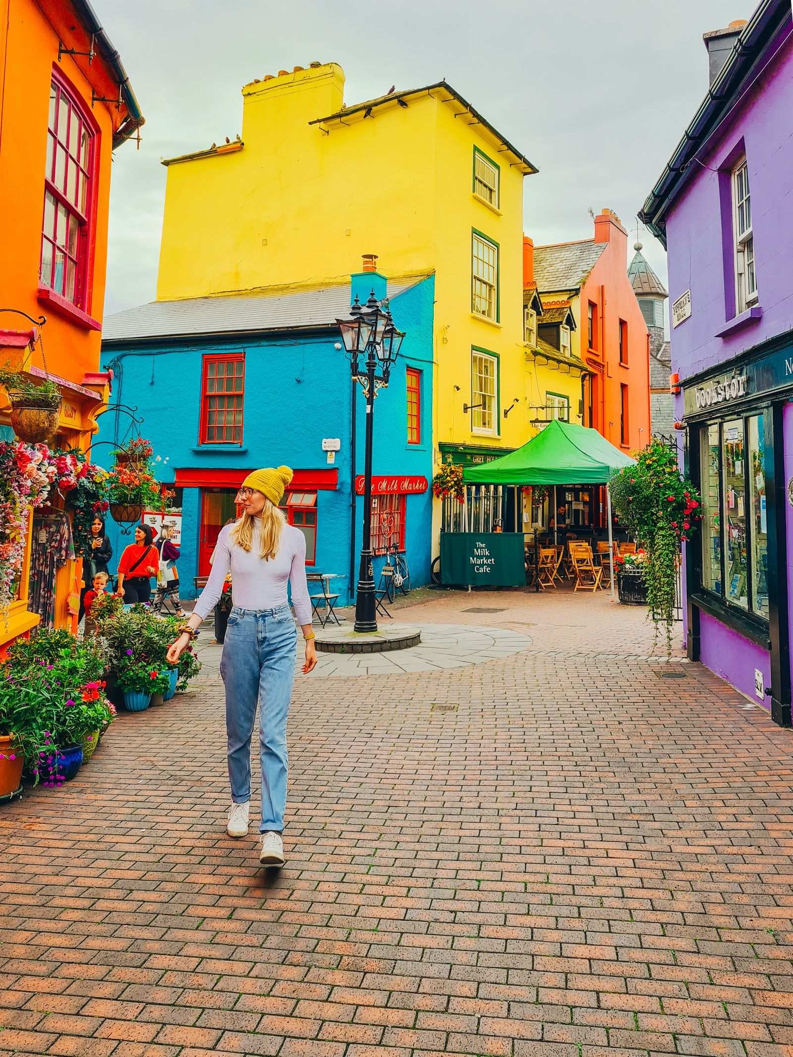Girl waling down brick street surrounded by many colourful buildings