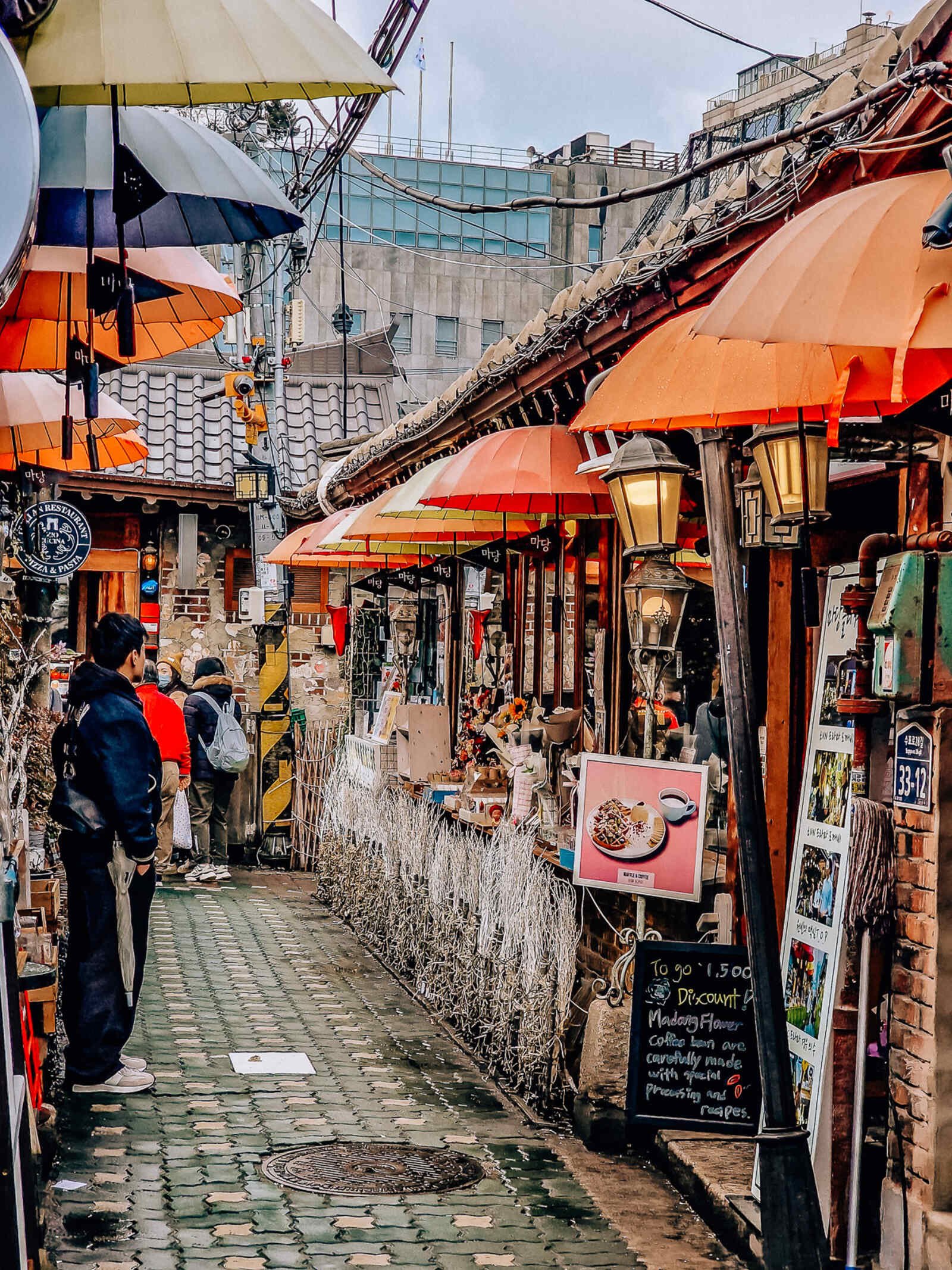 a narrow street lined with cafes with decorative orange umbrellas