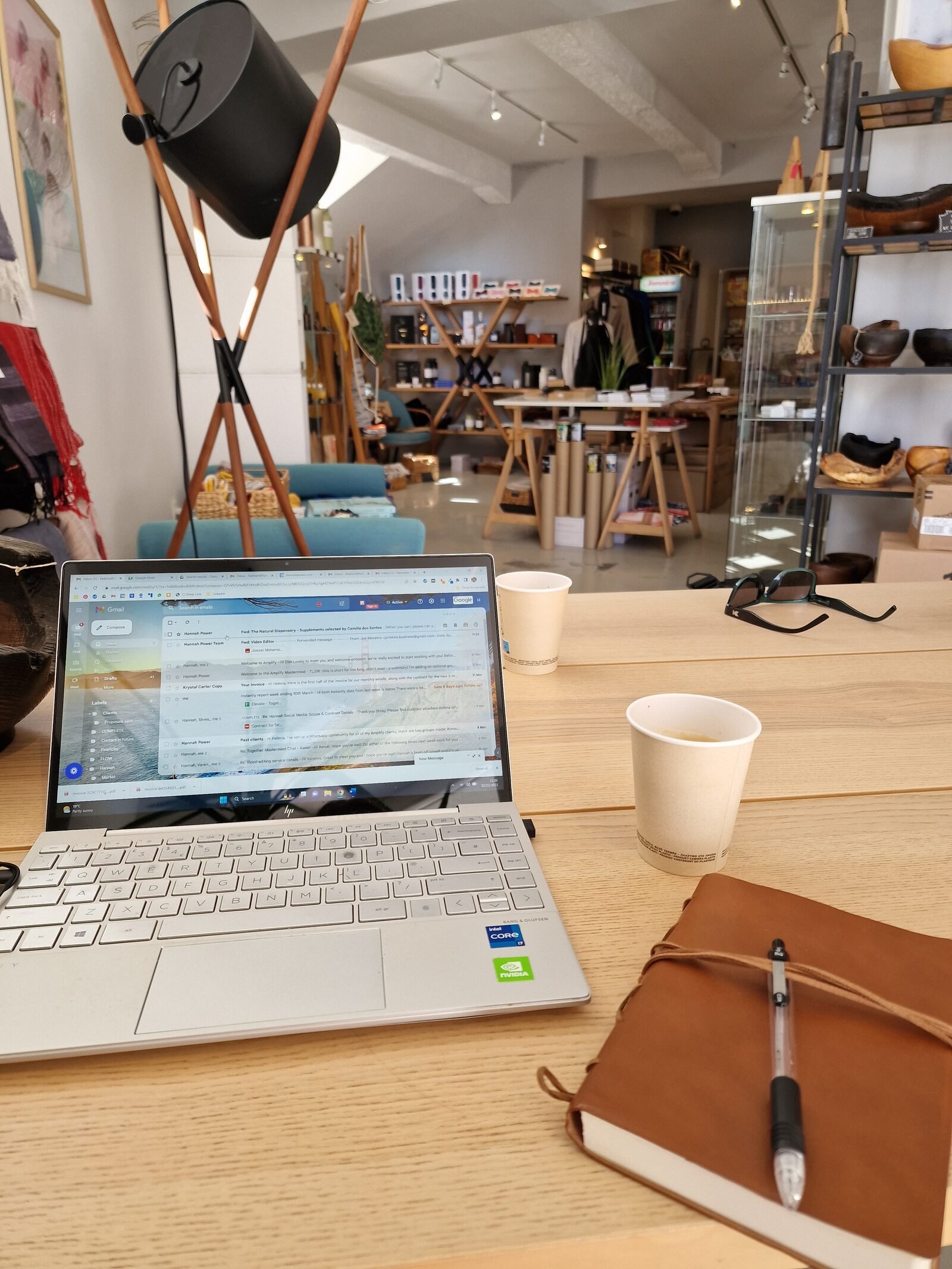 laptop, notepad and coffee on a table in a light and airy coffee shop