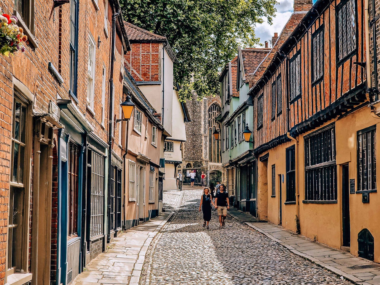A cobbled street lined with timber frame houses nd a church visible at the end of the street in Elm Hill Norwich on a England weekend away