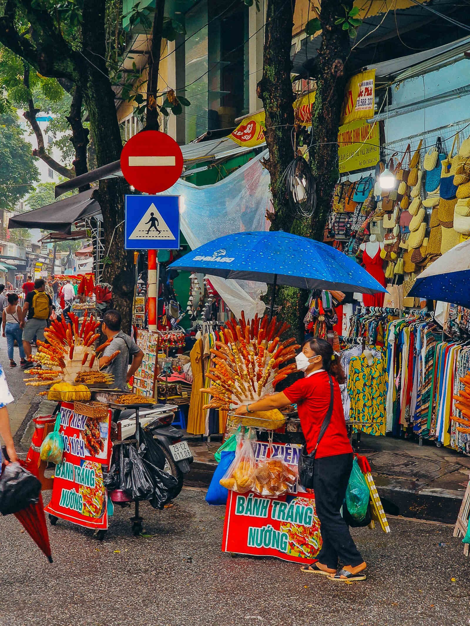 a woman standing next to her street food stand in Vietnam