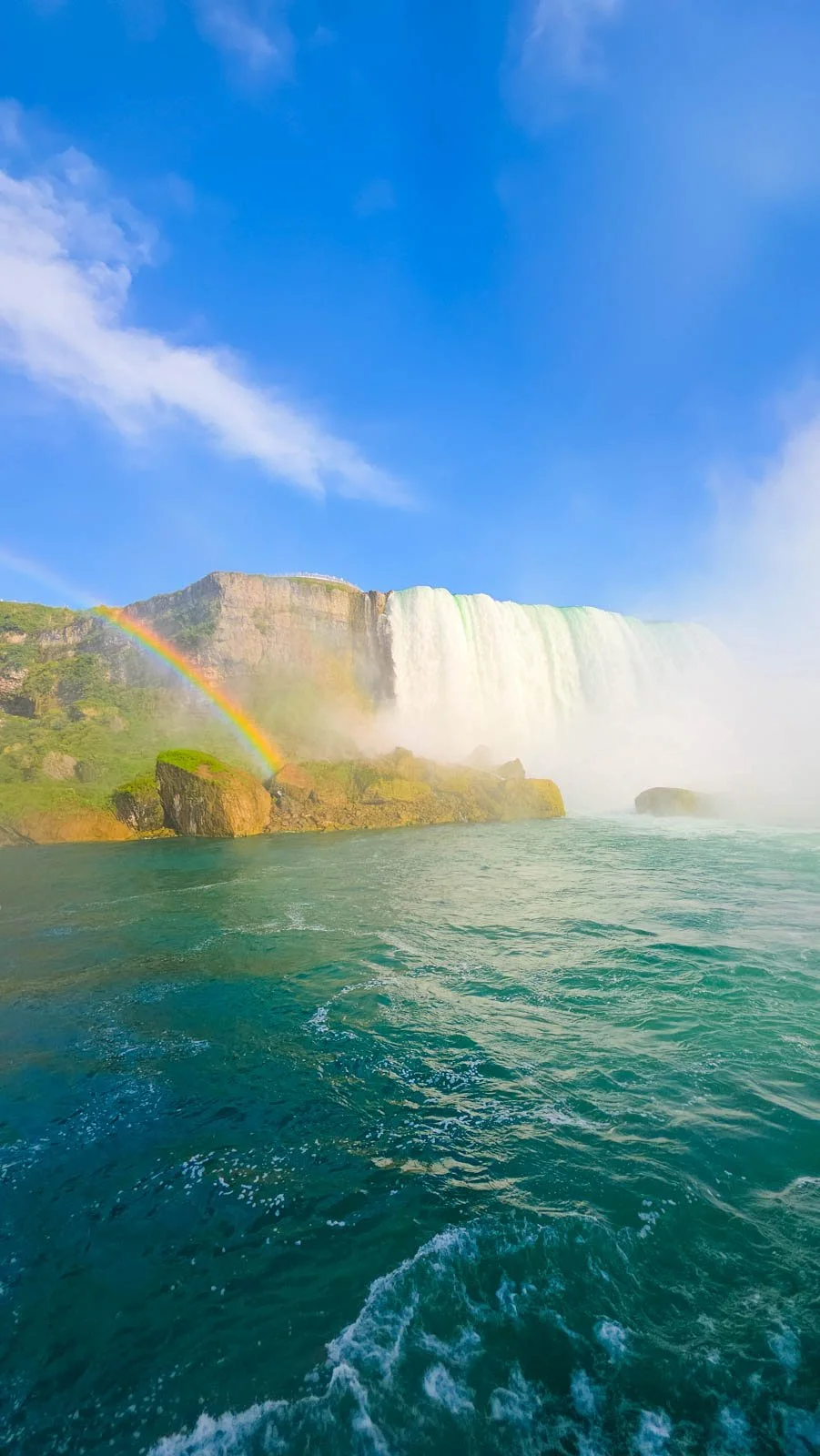 On the boat view of Niagara Falls with the blue waters and a rainbow