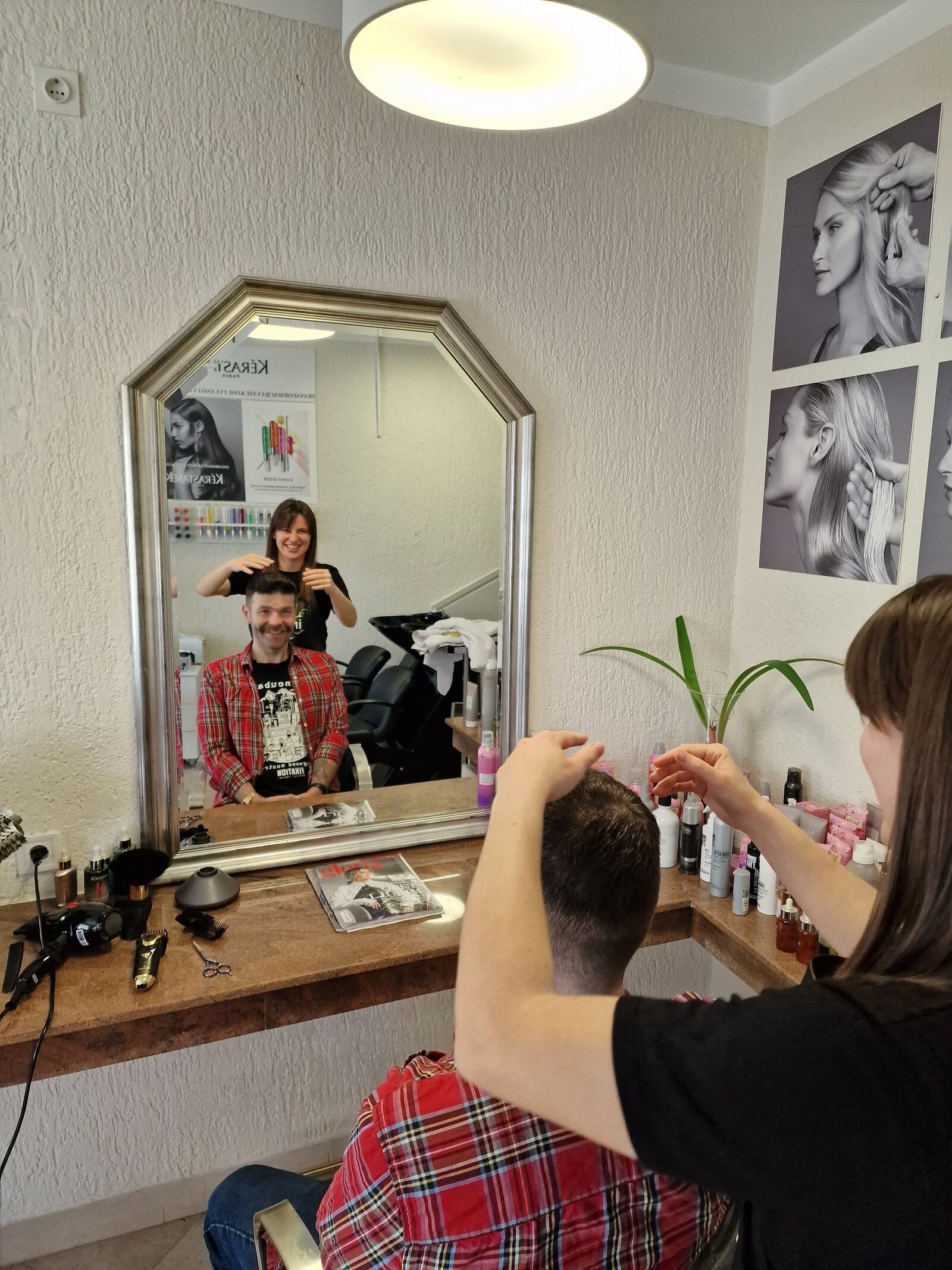 man getting his haircut by a woman reflected in a mirror