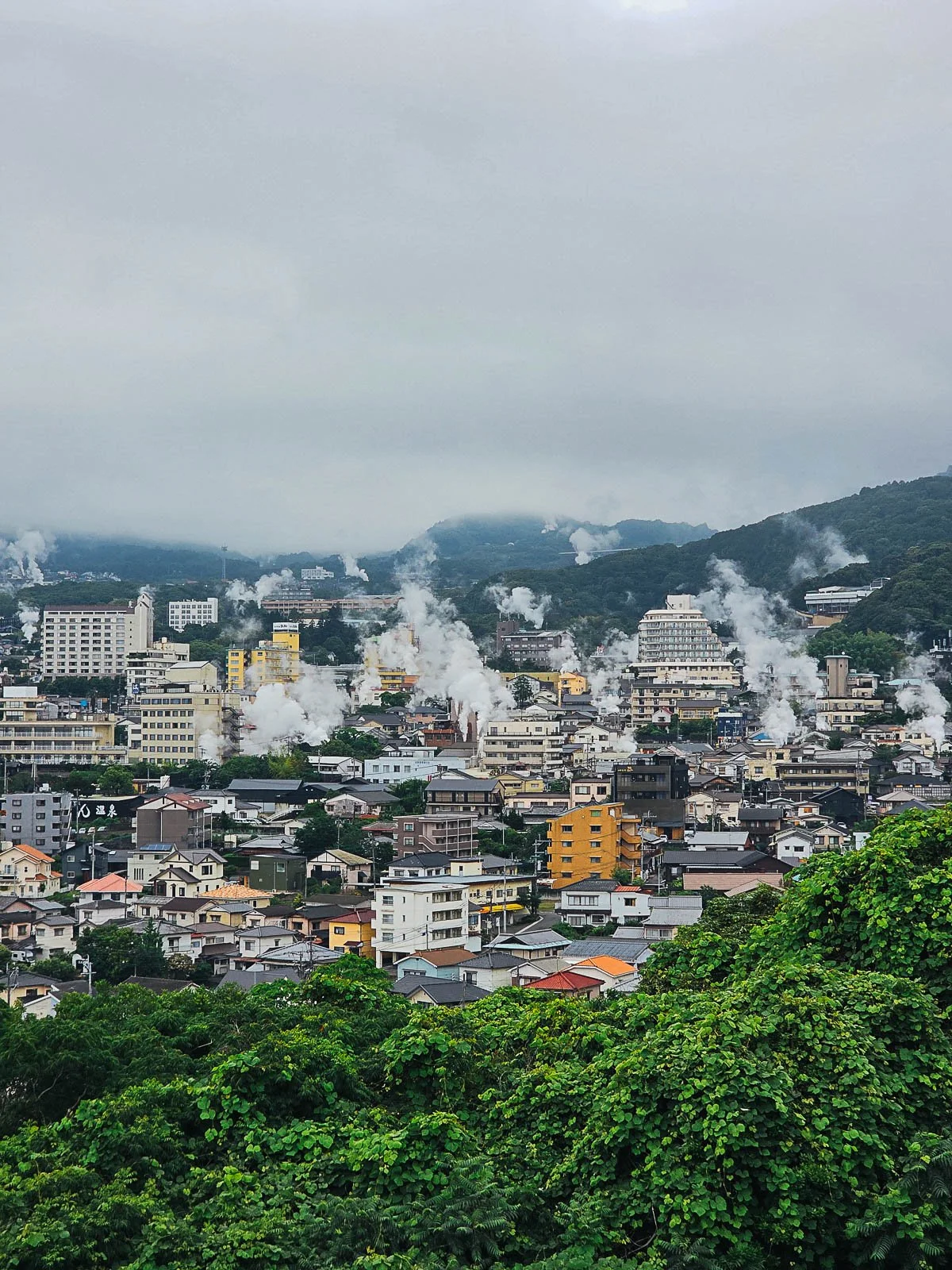 Plumes of steam rising above a city on a cloudy day