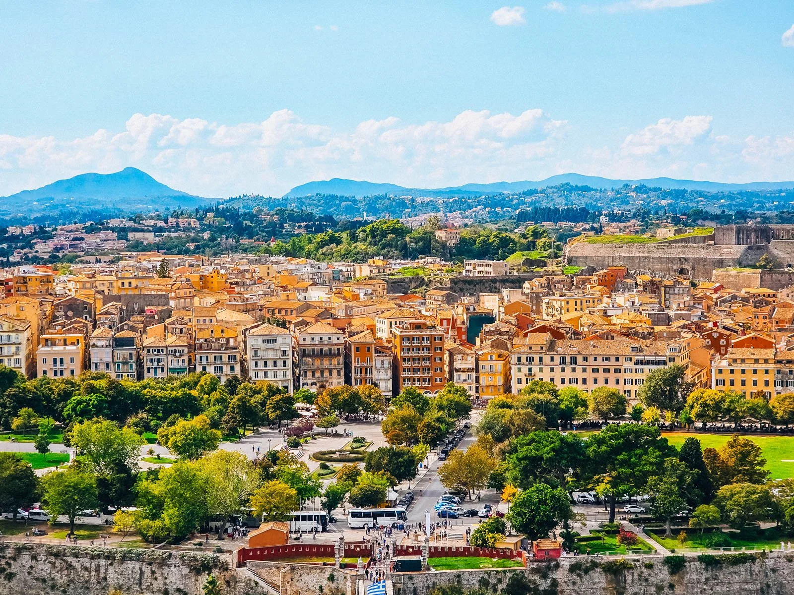 An aerial view of an old town with many buildings with a stone fort in the background.