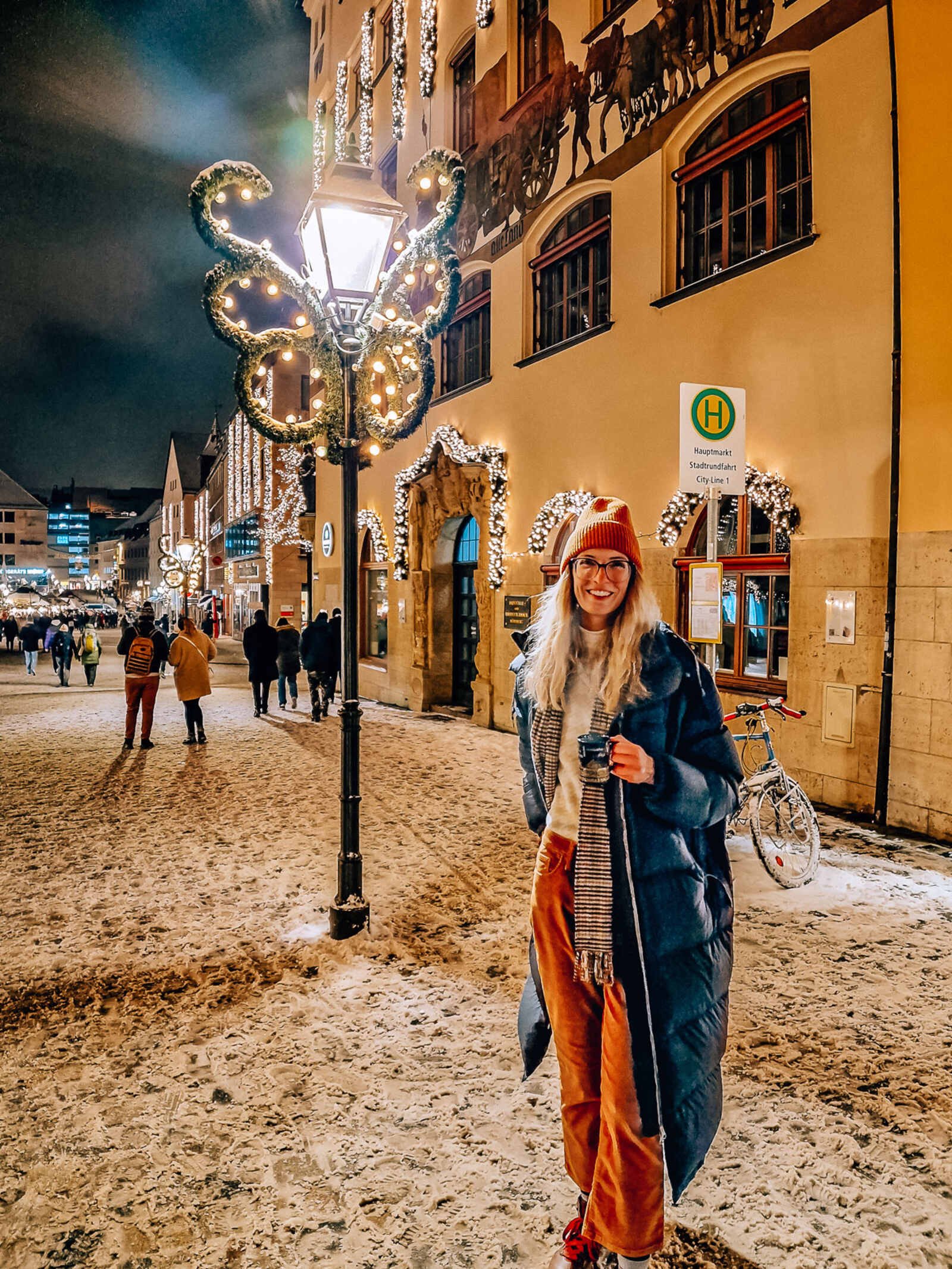 girl holding a mug in the snowy street at night in nuremberg