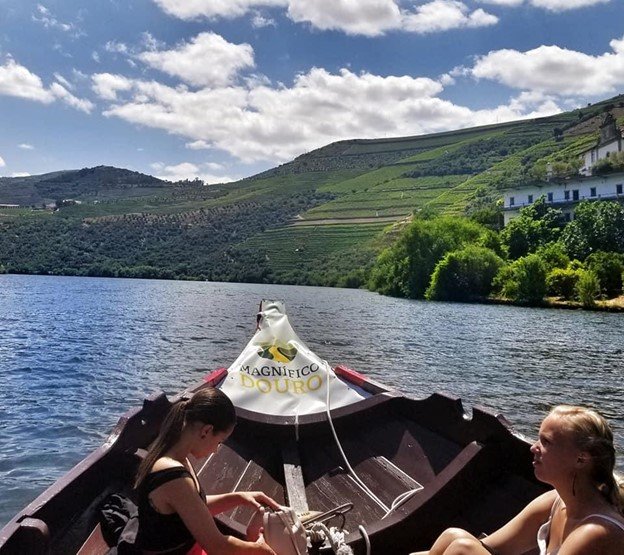 boat cruising on Douro river with green hills in the background on a day in the douro valley