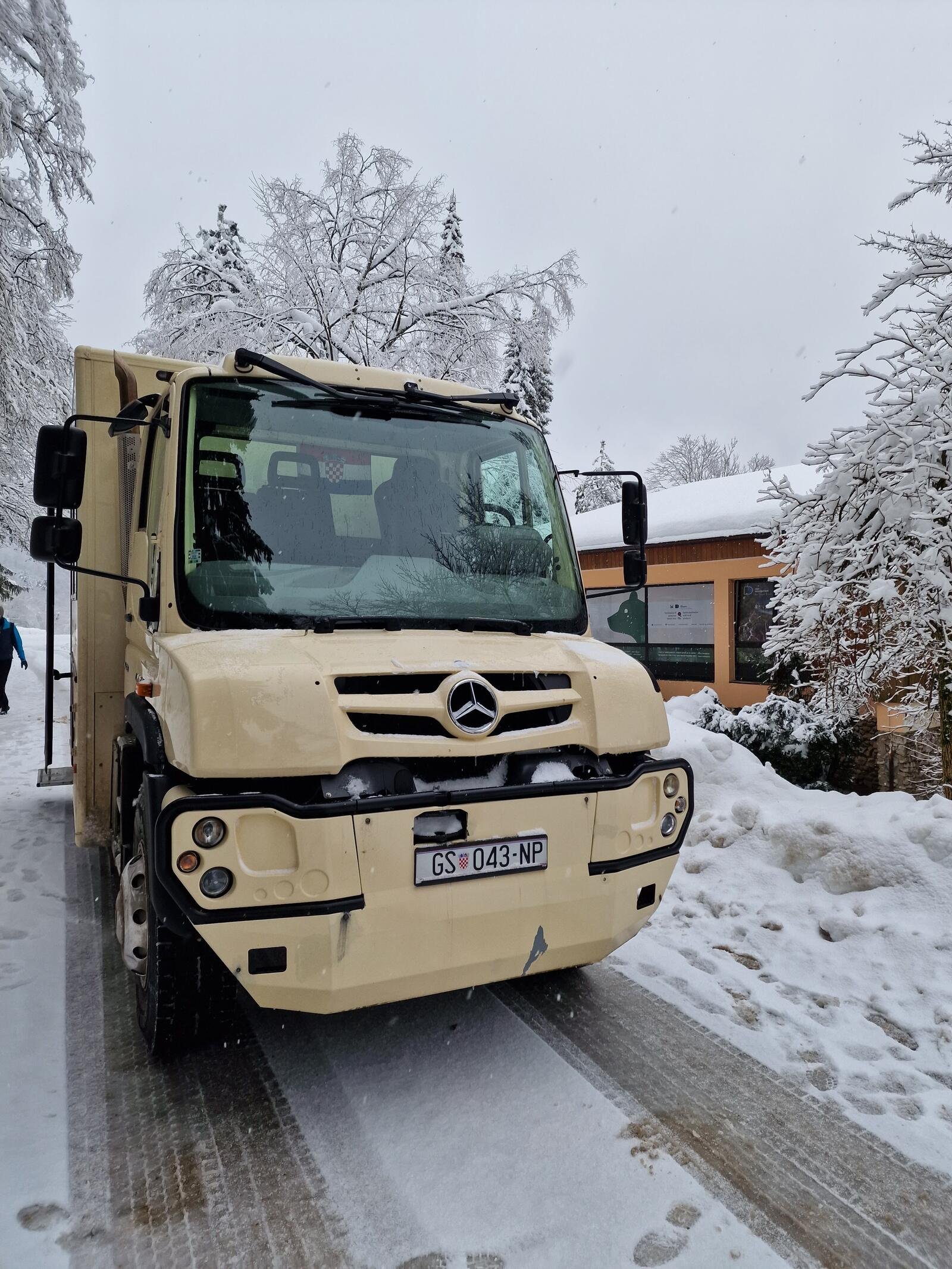 cream coloured Mercedes unimog off-road vehicle front view with huge wheels parked in the snow