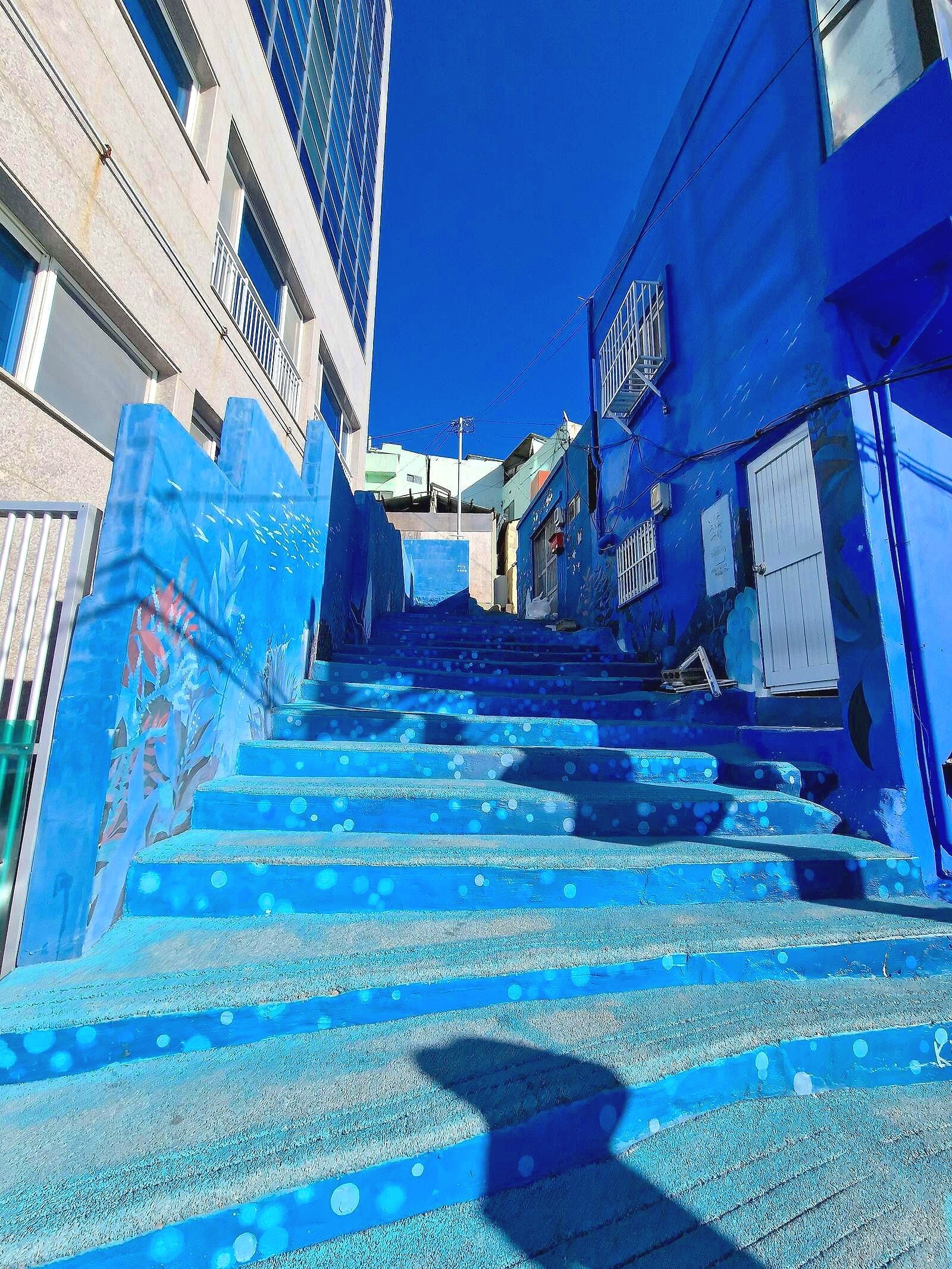 a stairway painted completely blue with a blue building on one side and a white one on the other