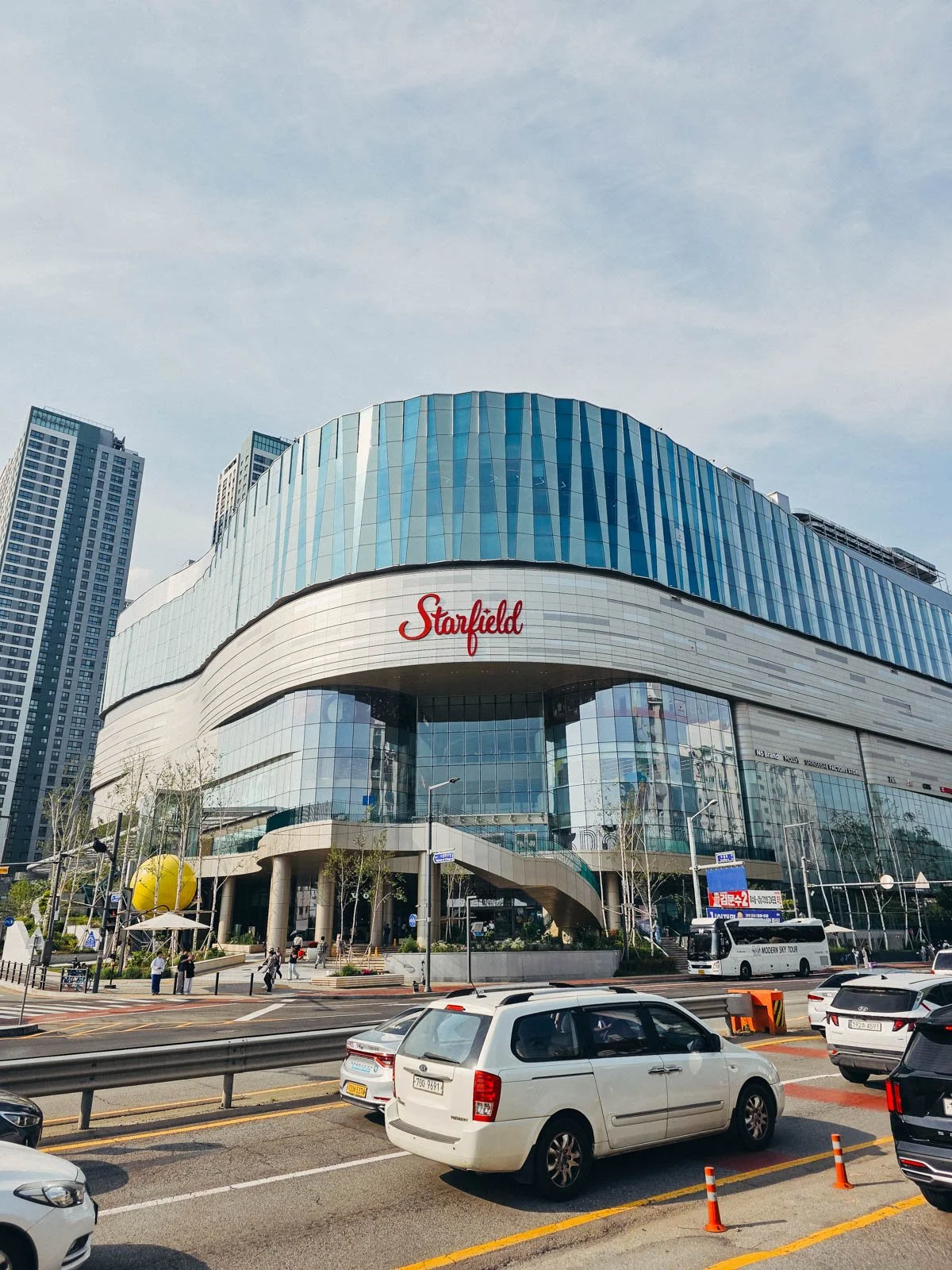 A large curved modern building covered in glass windows in the middle of a city