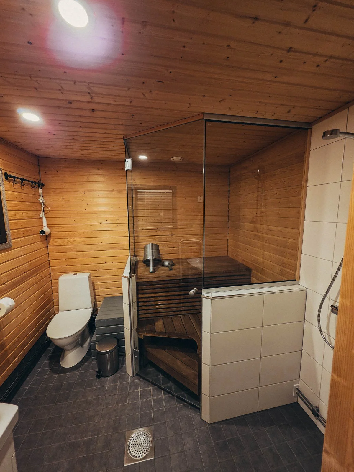 A large bathroom with wooden walls, toilet, and built in sauna