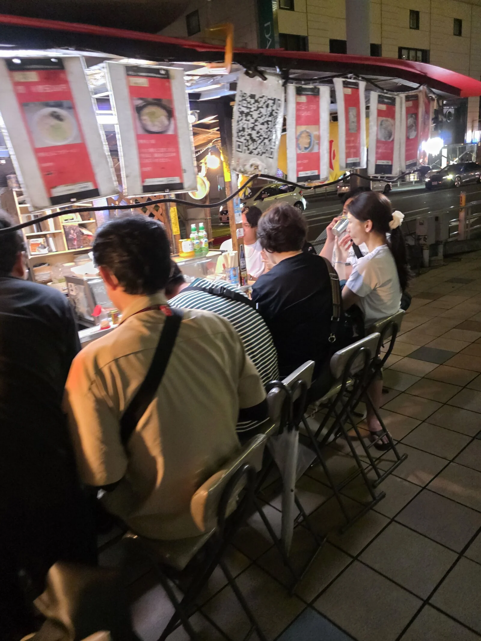 people sitting around a yatai food stall which is a pop up food stand in the street common in Fukuoka