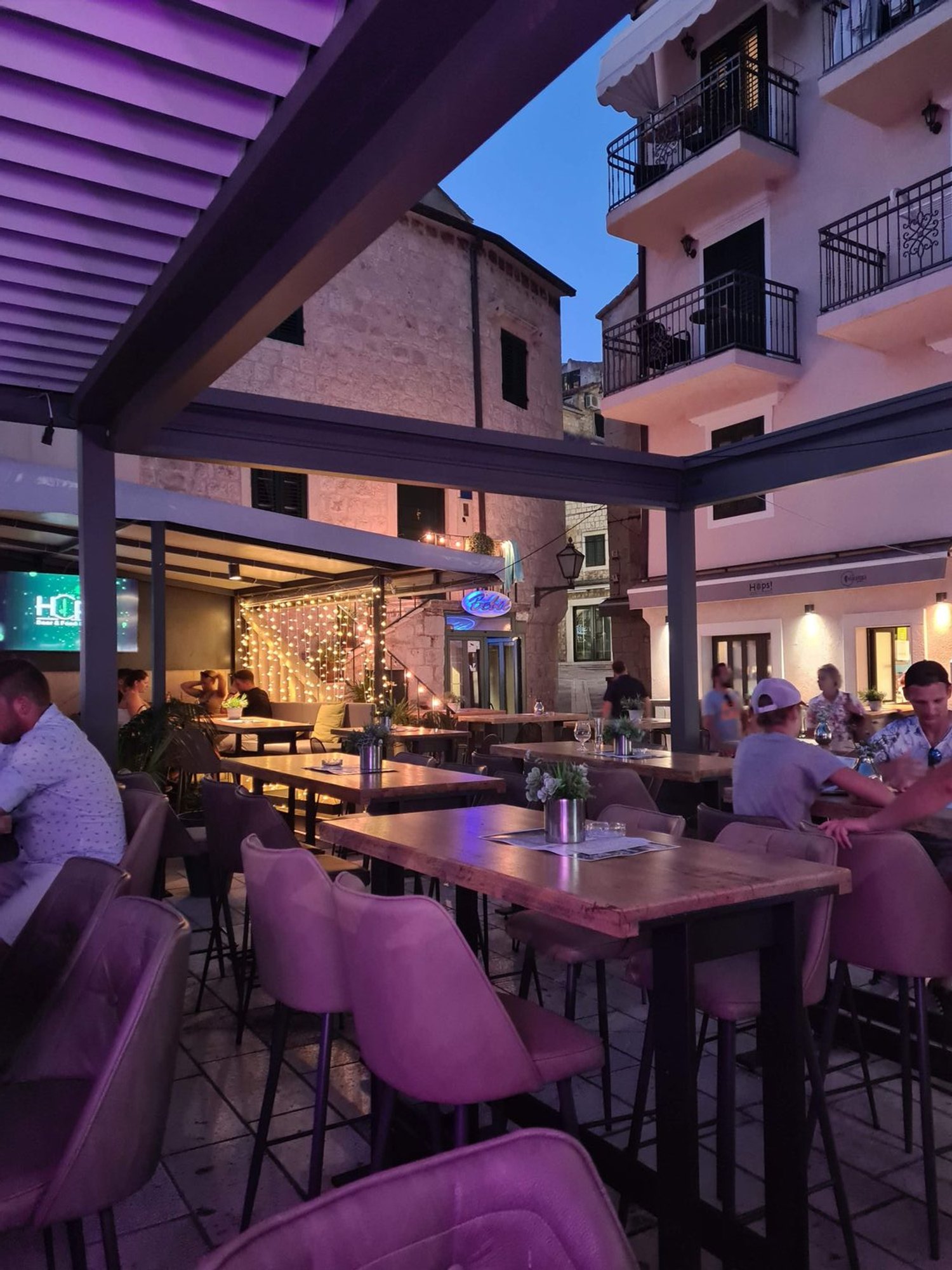 outdoor seating with purple lighting and people say at tables in a European town
