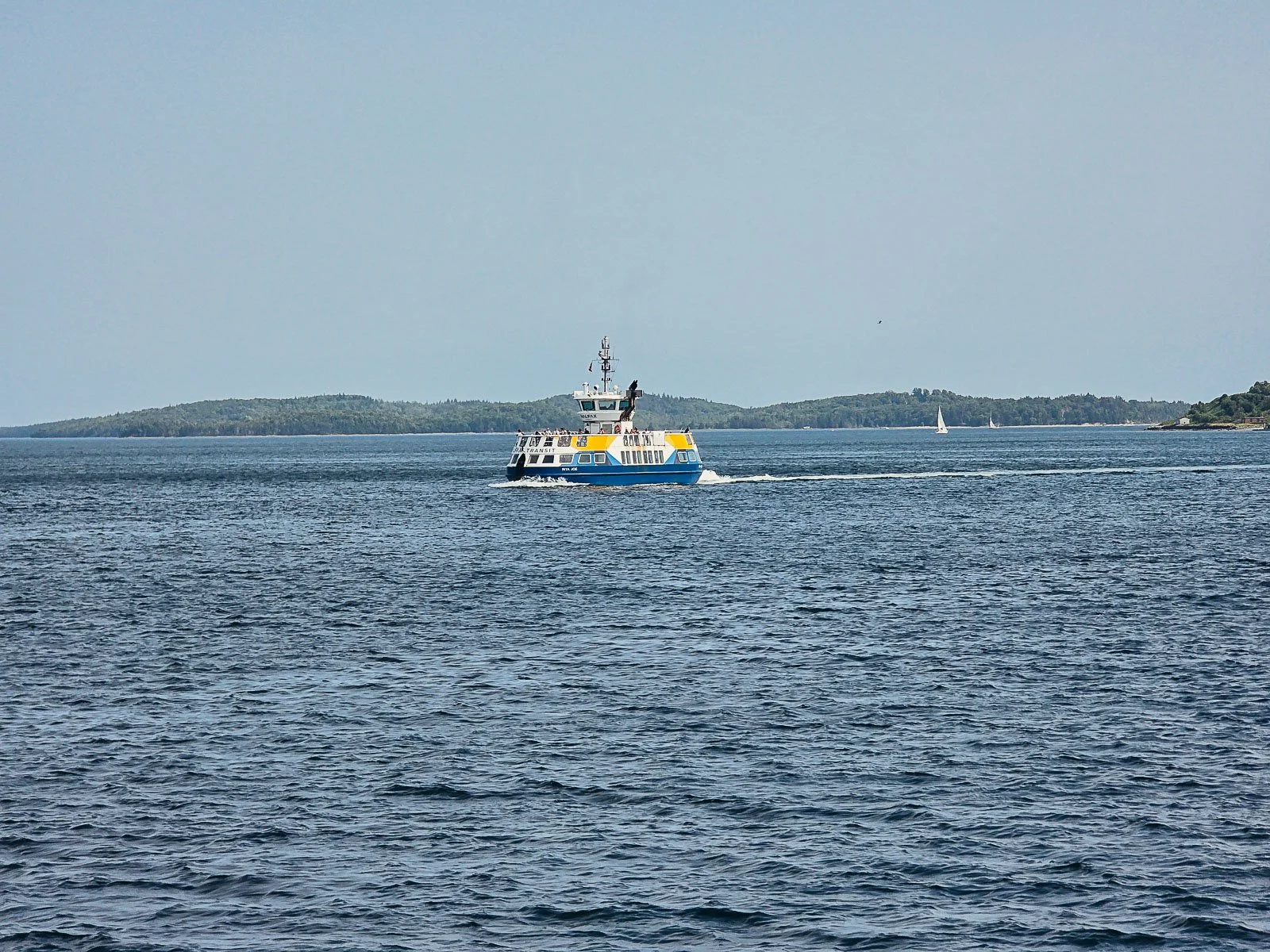 A large white and blue ferry surrounded by blue water