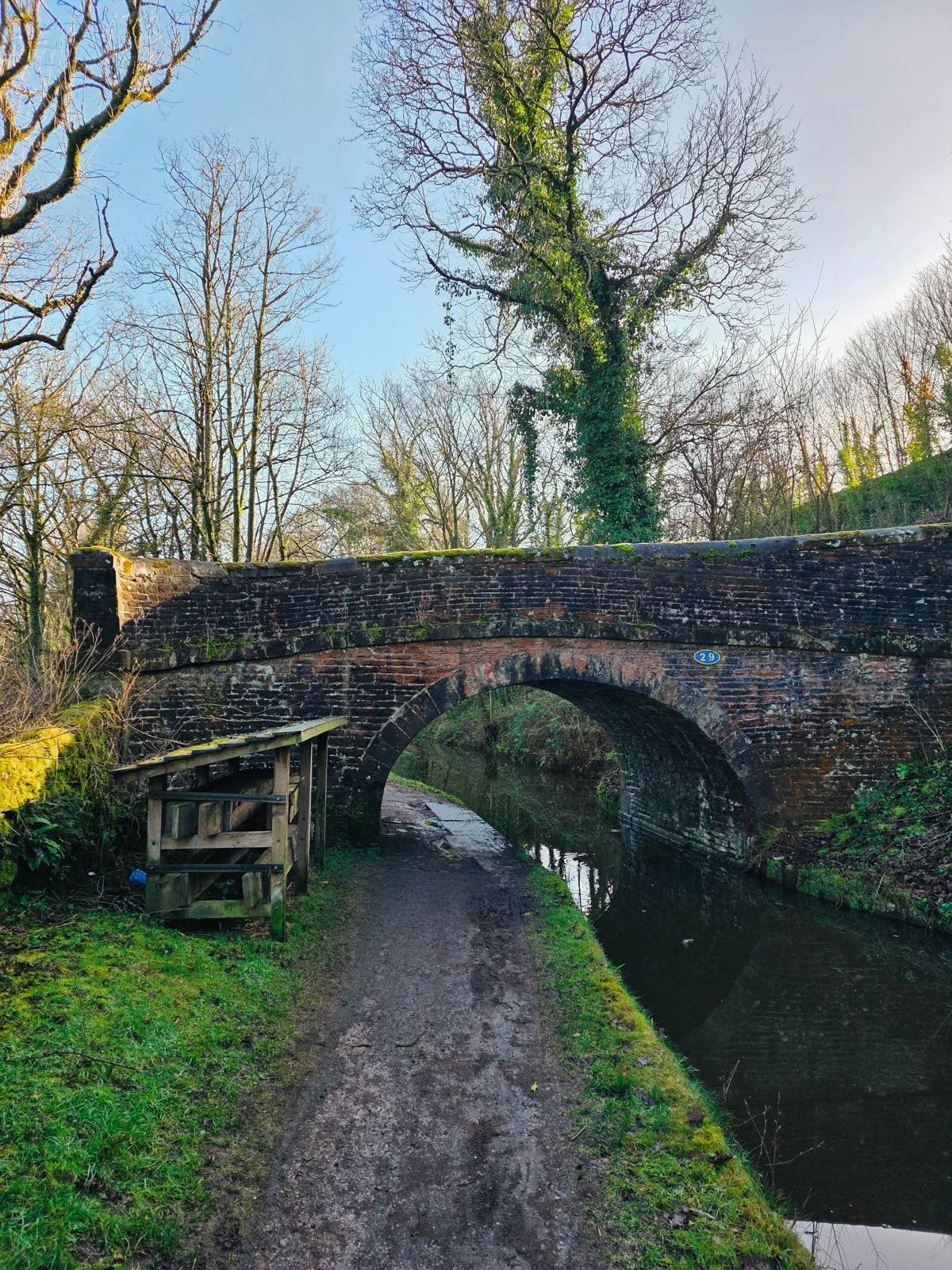 An old stone bridge over a canal with a path leading under it on the left side