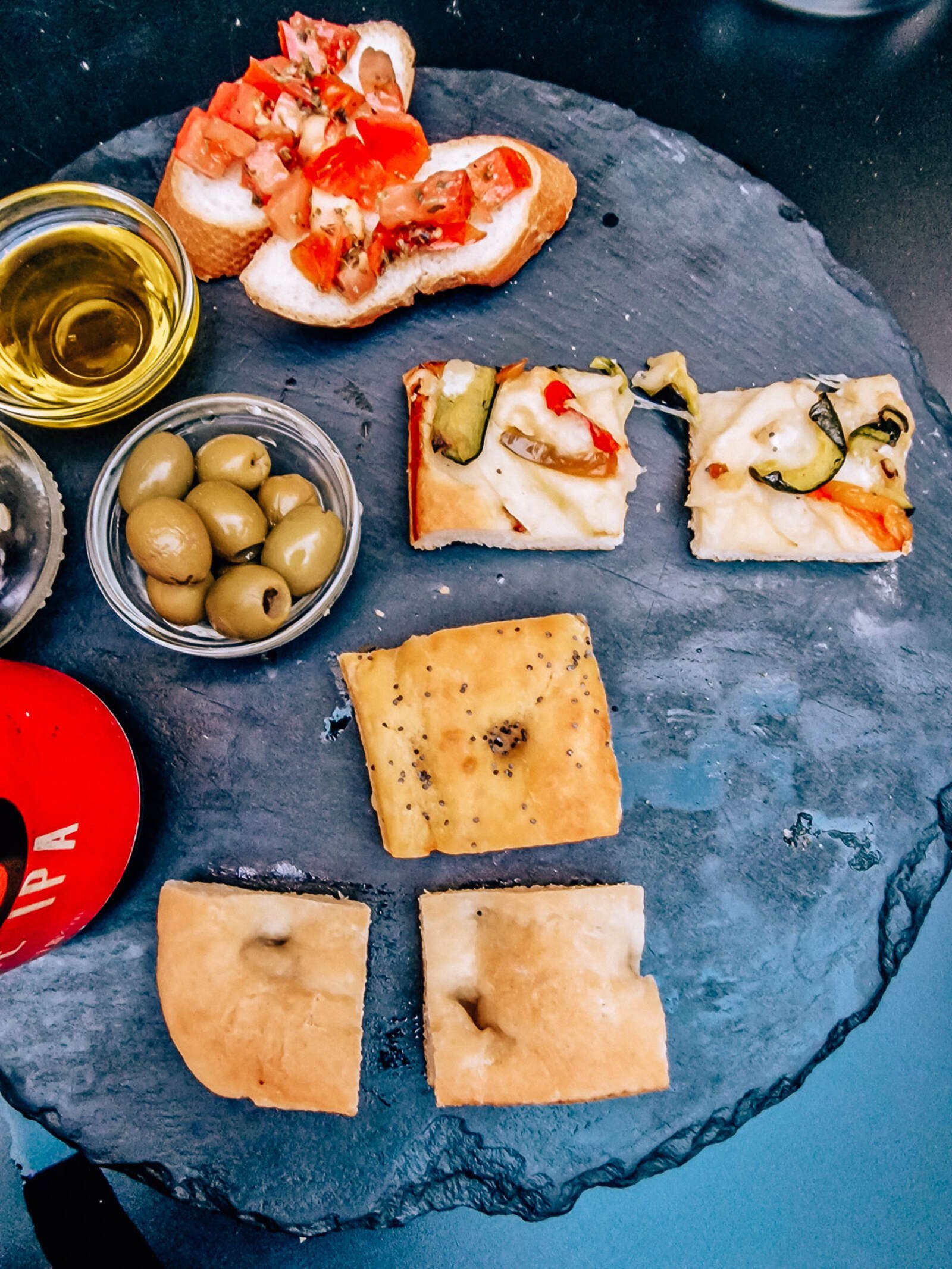 A stone plate with an assortment of Italian snack foods.