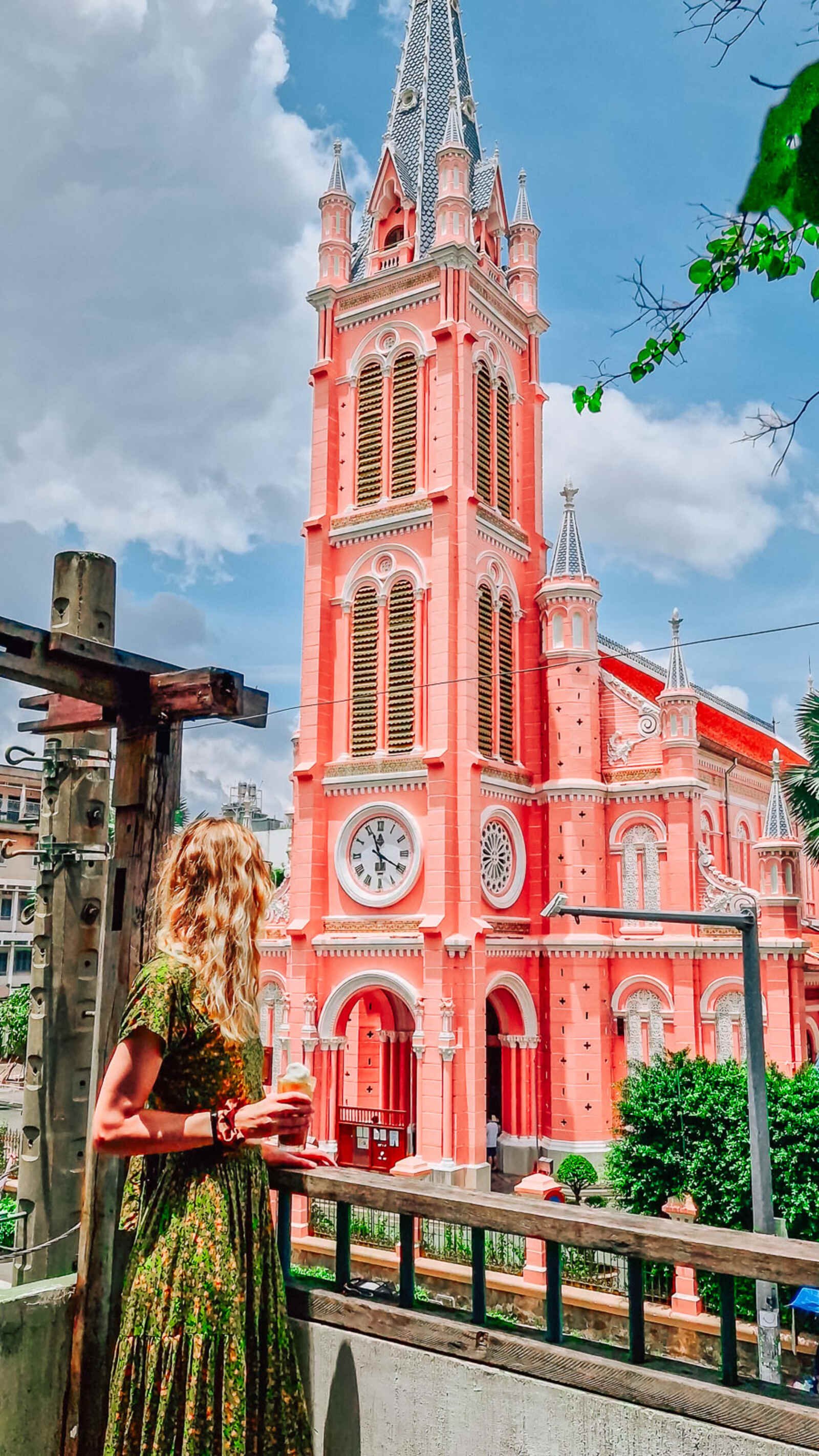 a coffee shop terrace with a view of a pink church in saigon