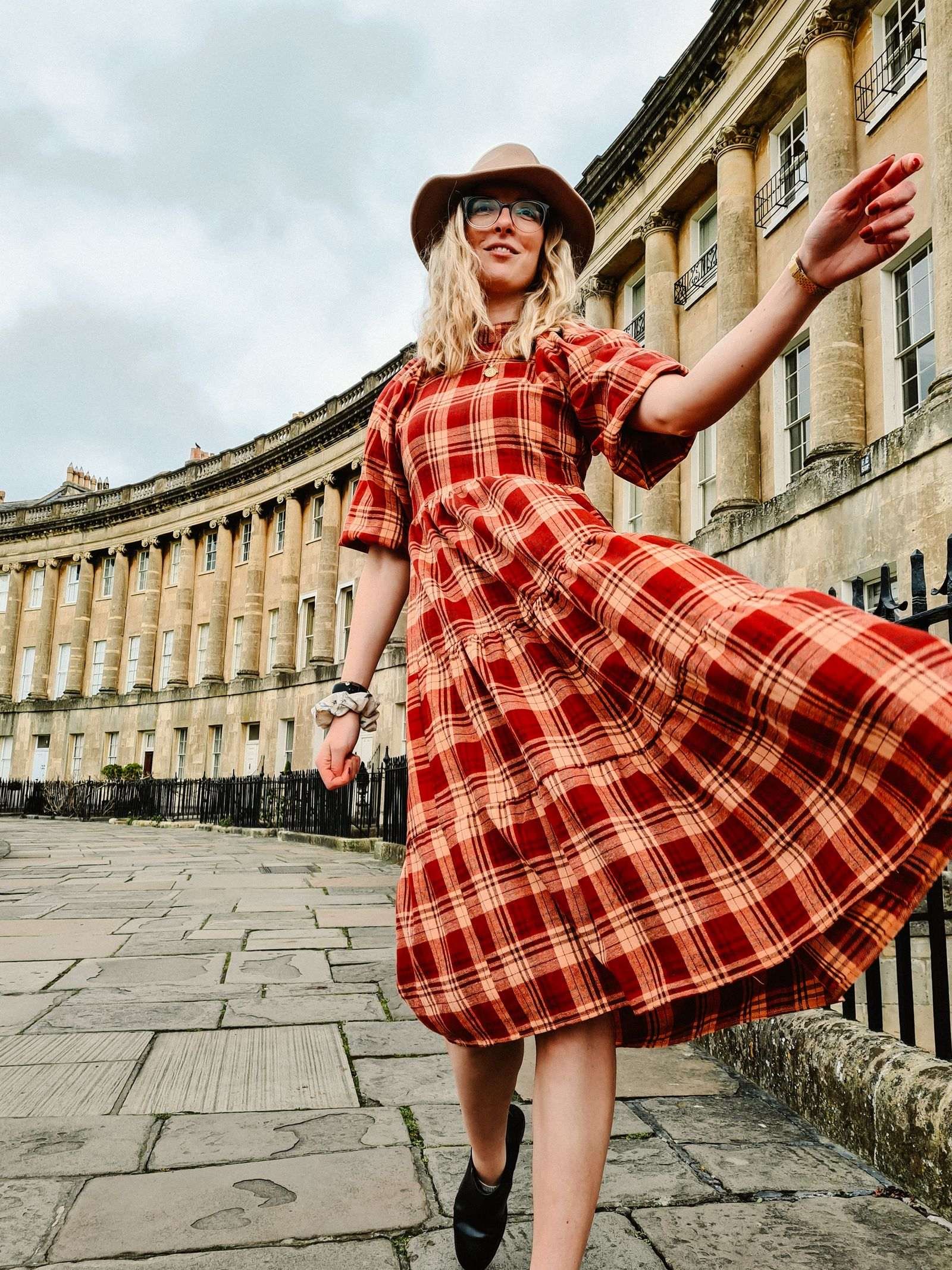 Girl in red dress flicking skirt in Bath's Royal Crescent