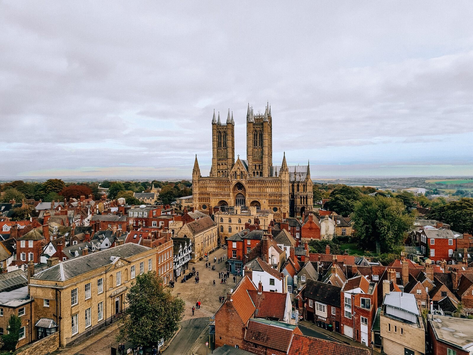 an aerial view of lincoln ciy with the cathedral towering over small houses and narrow cobbled streets on a cloudy day