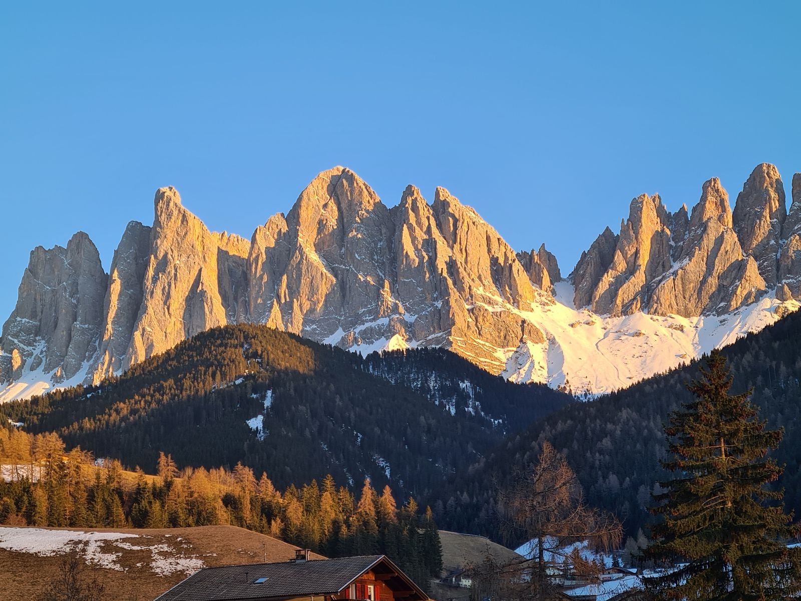 jagged mountains in the Italian dolomites, covered in snow and glowing orange at sunset