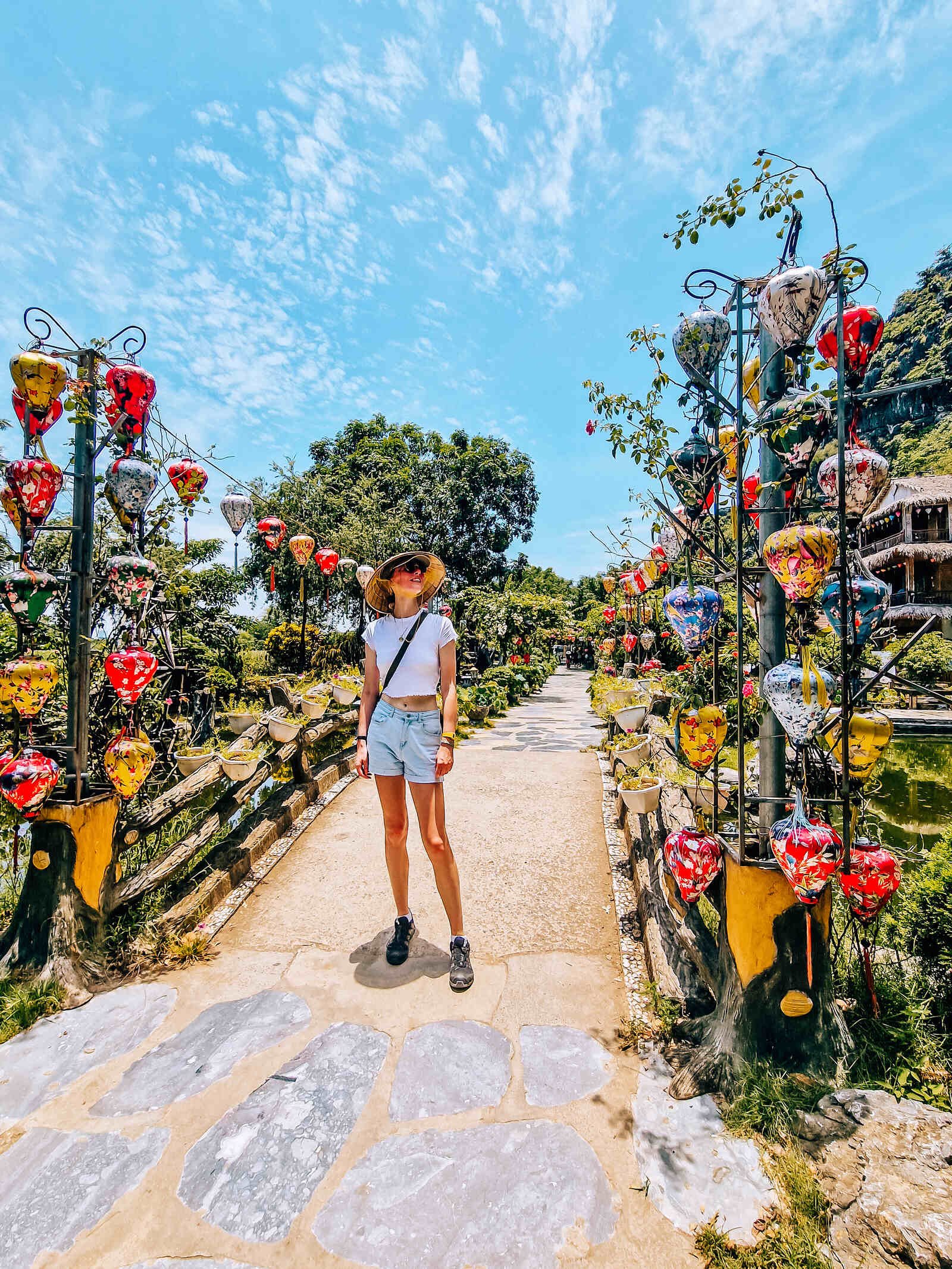 Helena standing on a stone bridge decorated in yellow, pink and white vietnamese lanterns