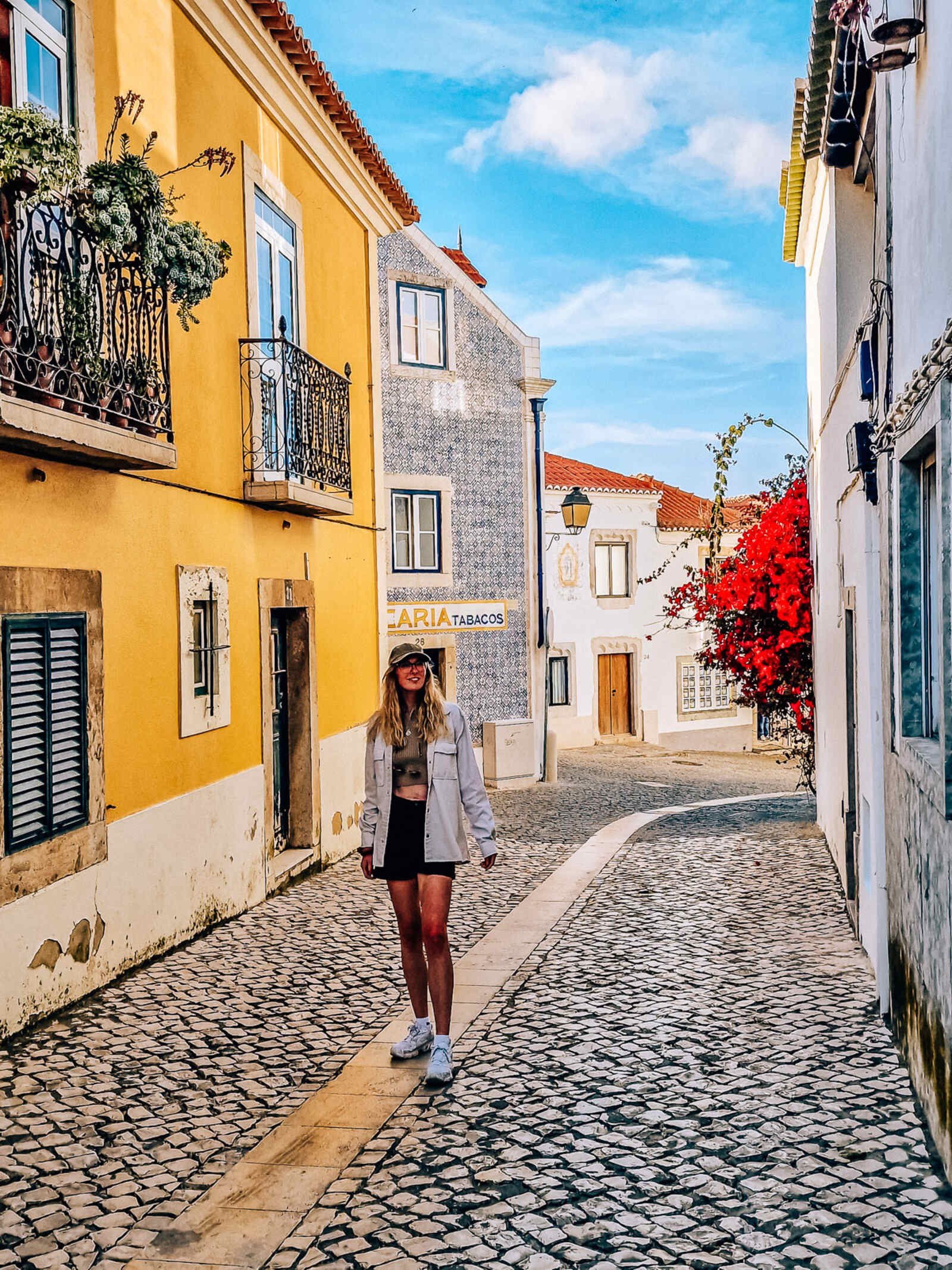woman walking along a colourful cobbled street in Cascais