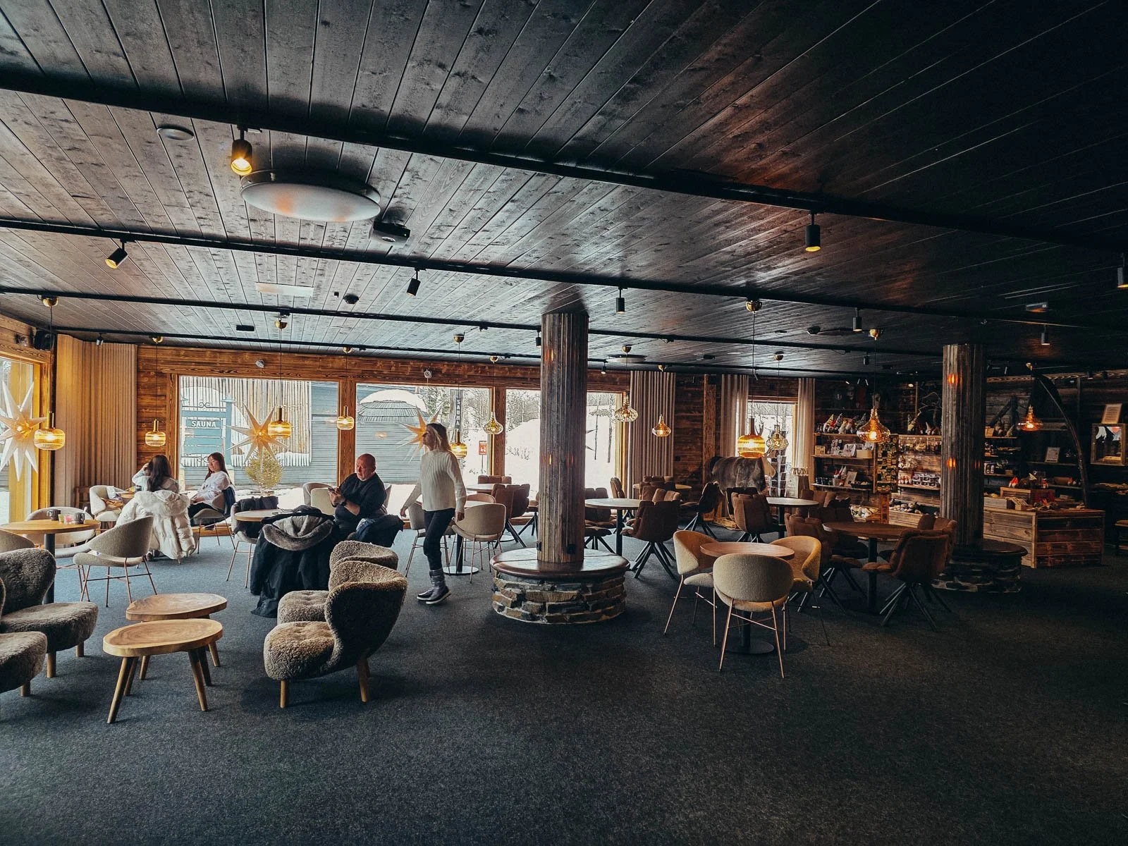 A large dark wooden interior of a hotel lobby in Rovaniemi with many tables and chairs