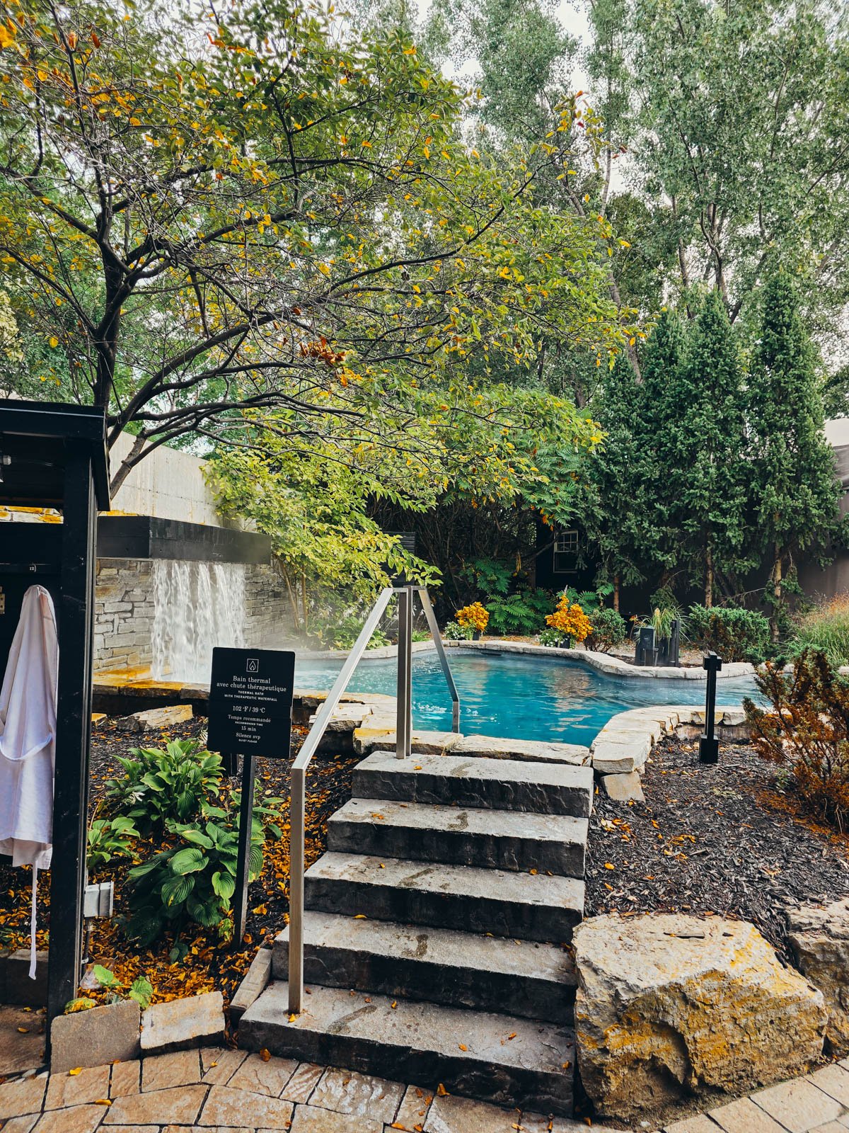 Steps leading up to a steaming pool surrounded by trees at Strom Spa - one of the best things to do in Montreal