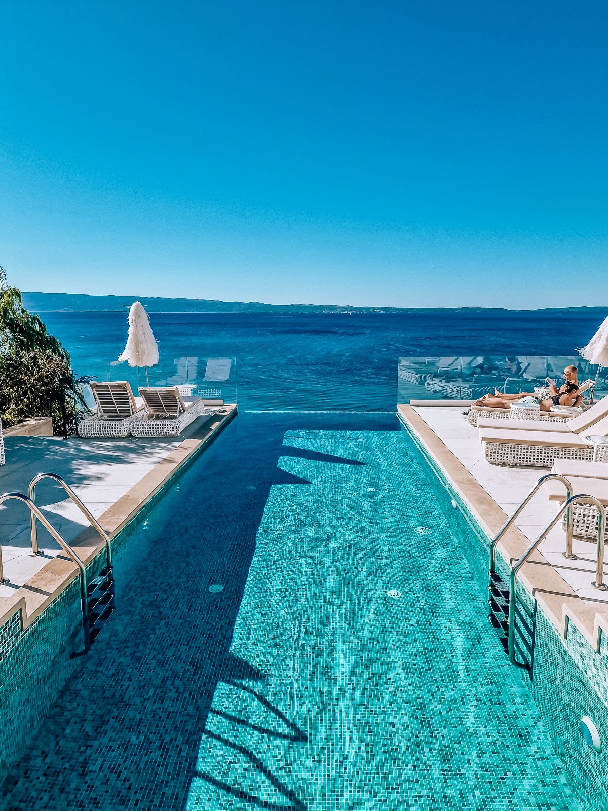 Turquoise infinity pool looking out at blue sea and sky
