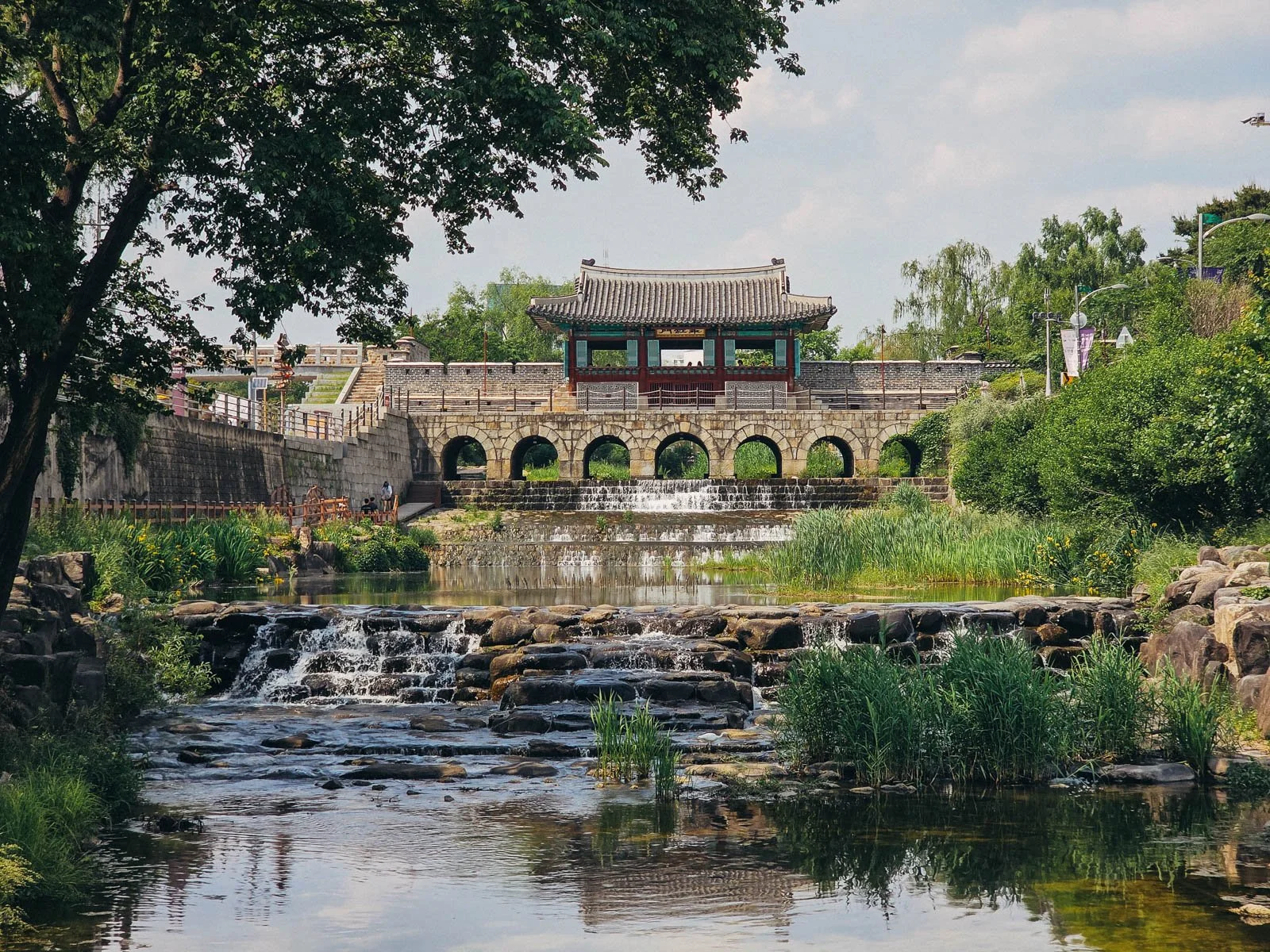 A large stone fortress wall sitting on top of a wide flowing river.