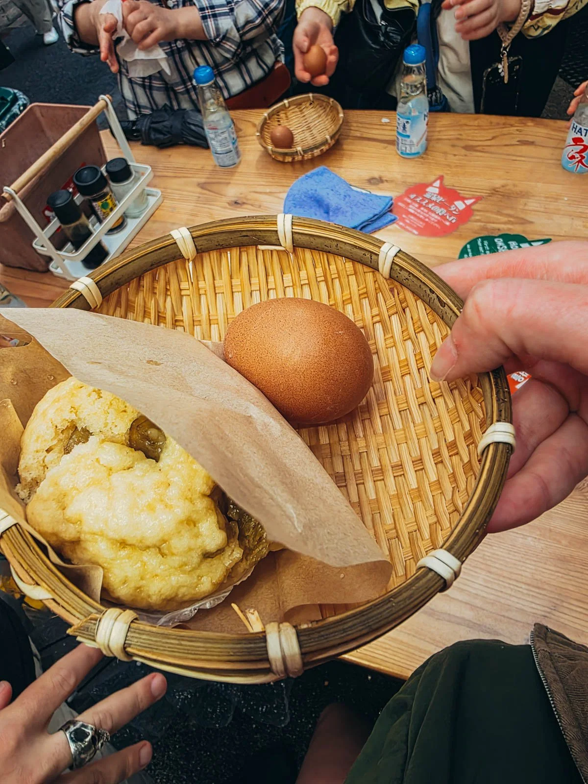 Hands holding a wicker basket with a steamed bun and egg at the Hells of Beppu