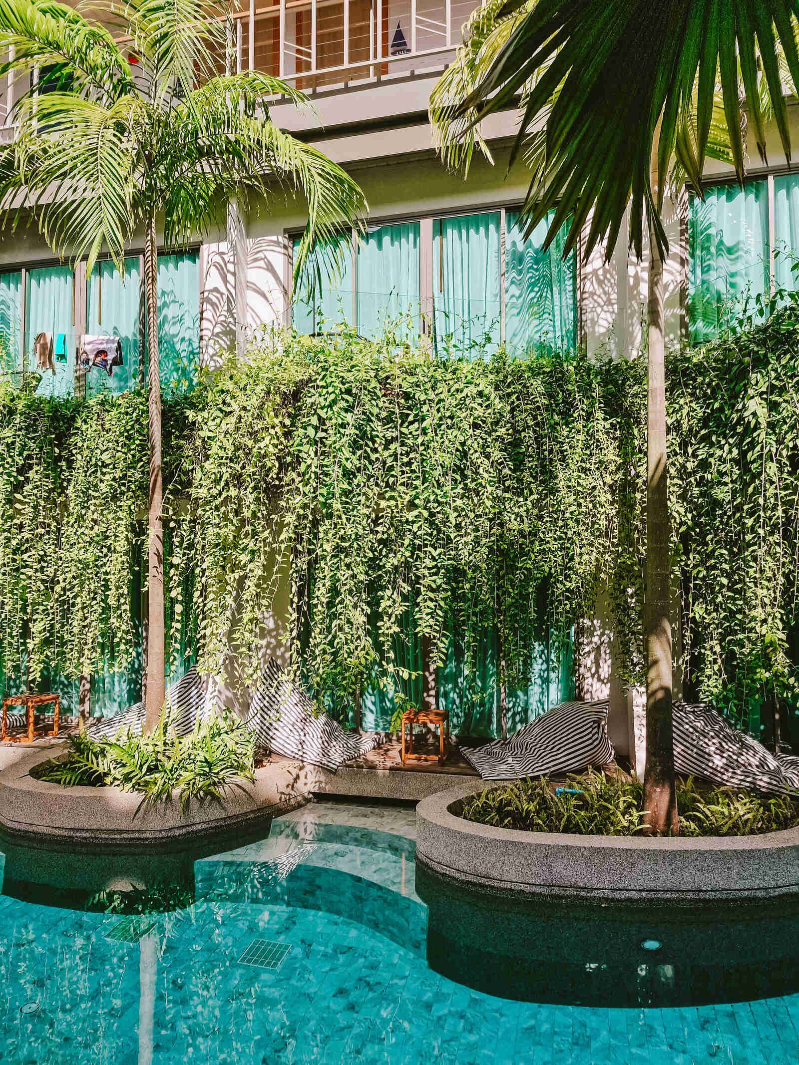 a pool with steps leading straight to a hotel room deck and door covered wiih green hanging vines