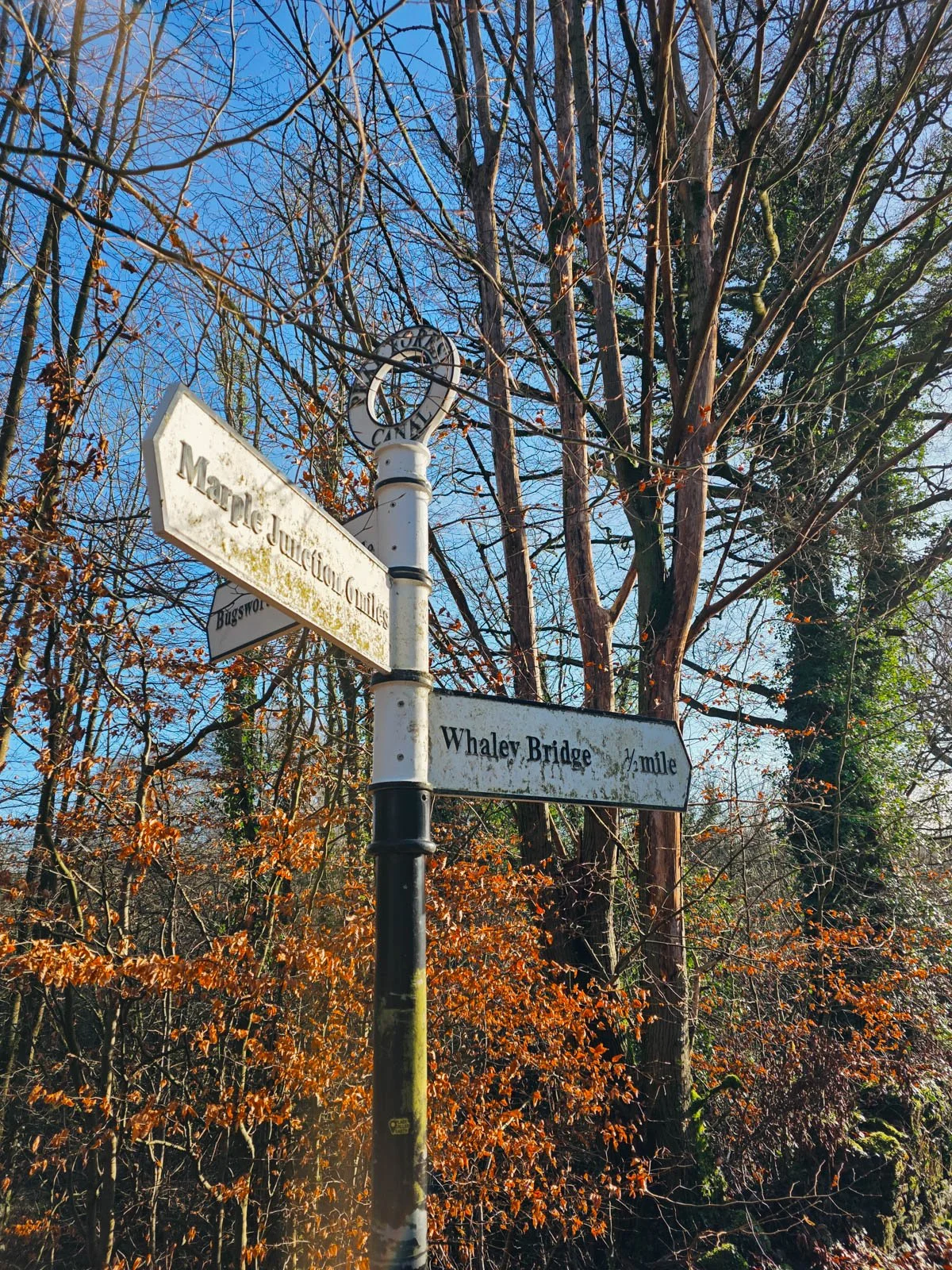 a millmarker with signs pointing right to Whaley Brdige and left to Marple Junction