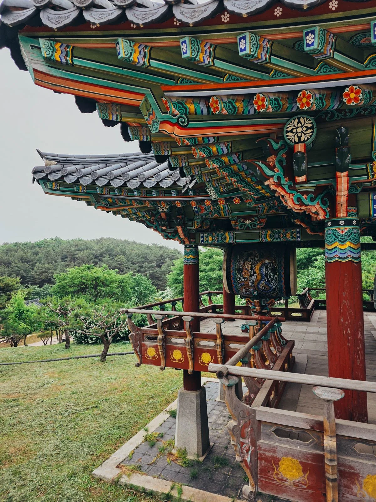 The upper tier of an intricately colourful temple in Sokcho, South Korea with a large drum hanging from the ceiling