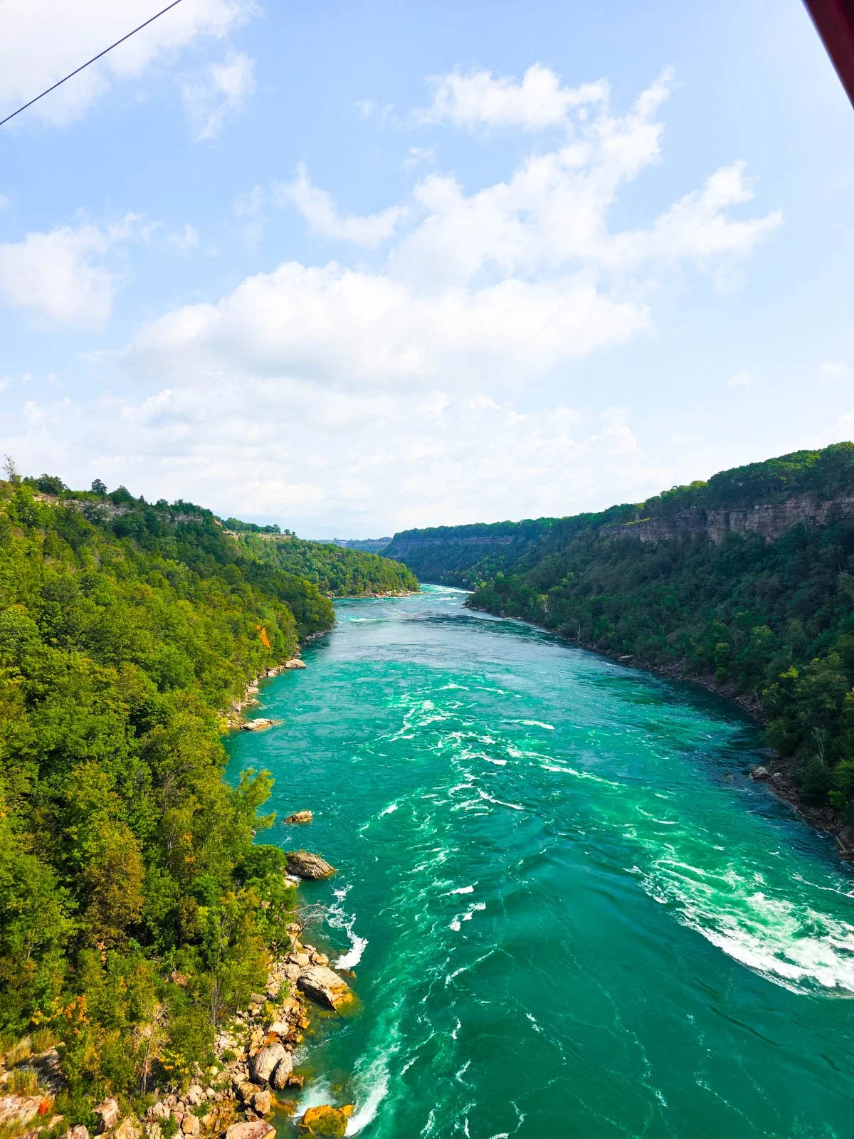 A river gorge with a vibrant turquoise river and trees on both river banks