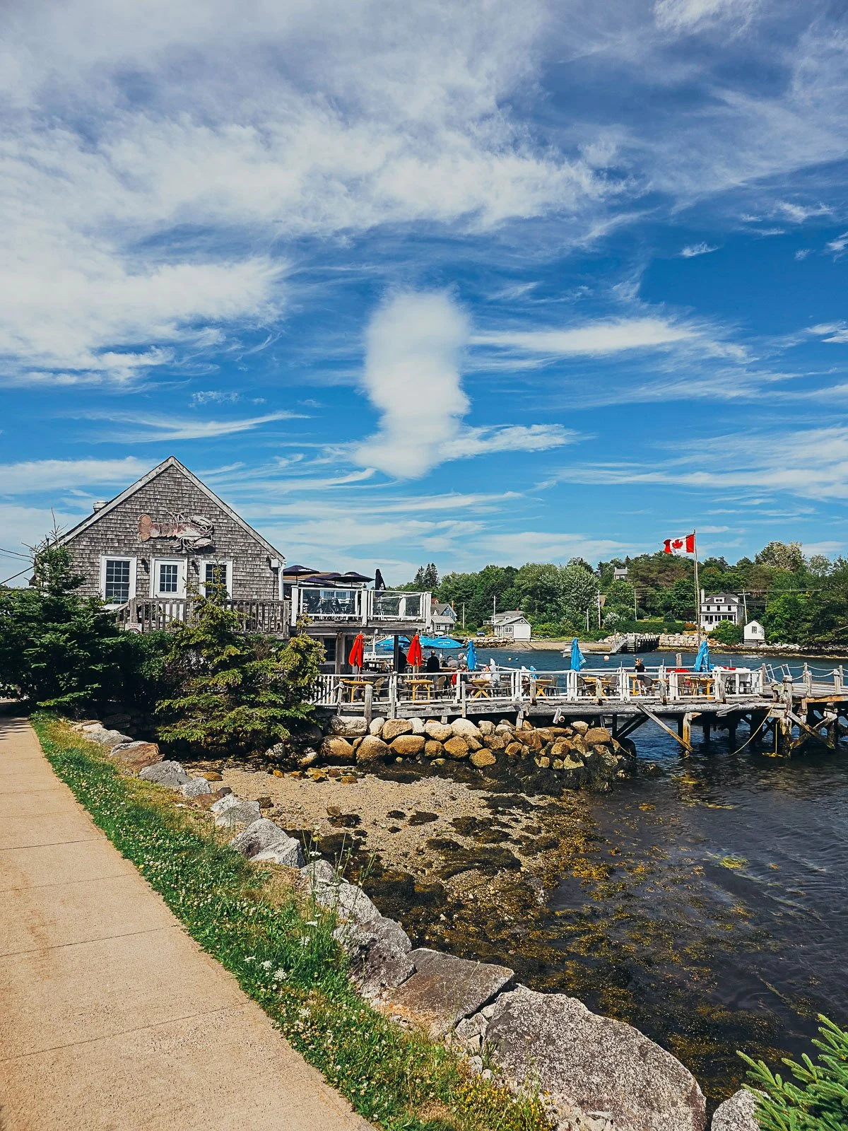 a waterfront restaurant with outdoor dining on a dock that stretches into the harbour on a sunny day