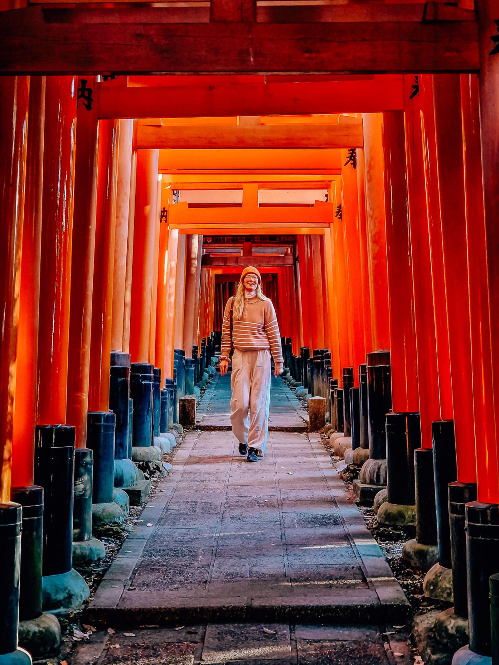 Helena walking down a path with orange arches all the way along - Japanese torii gates