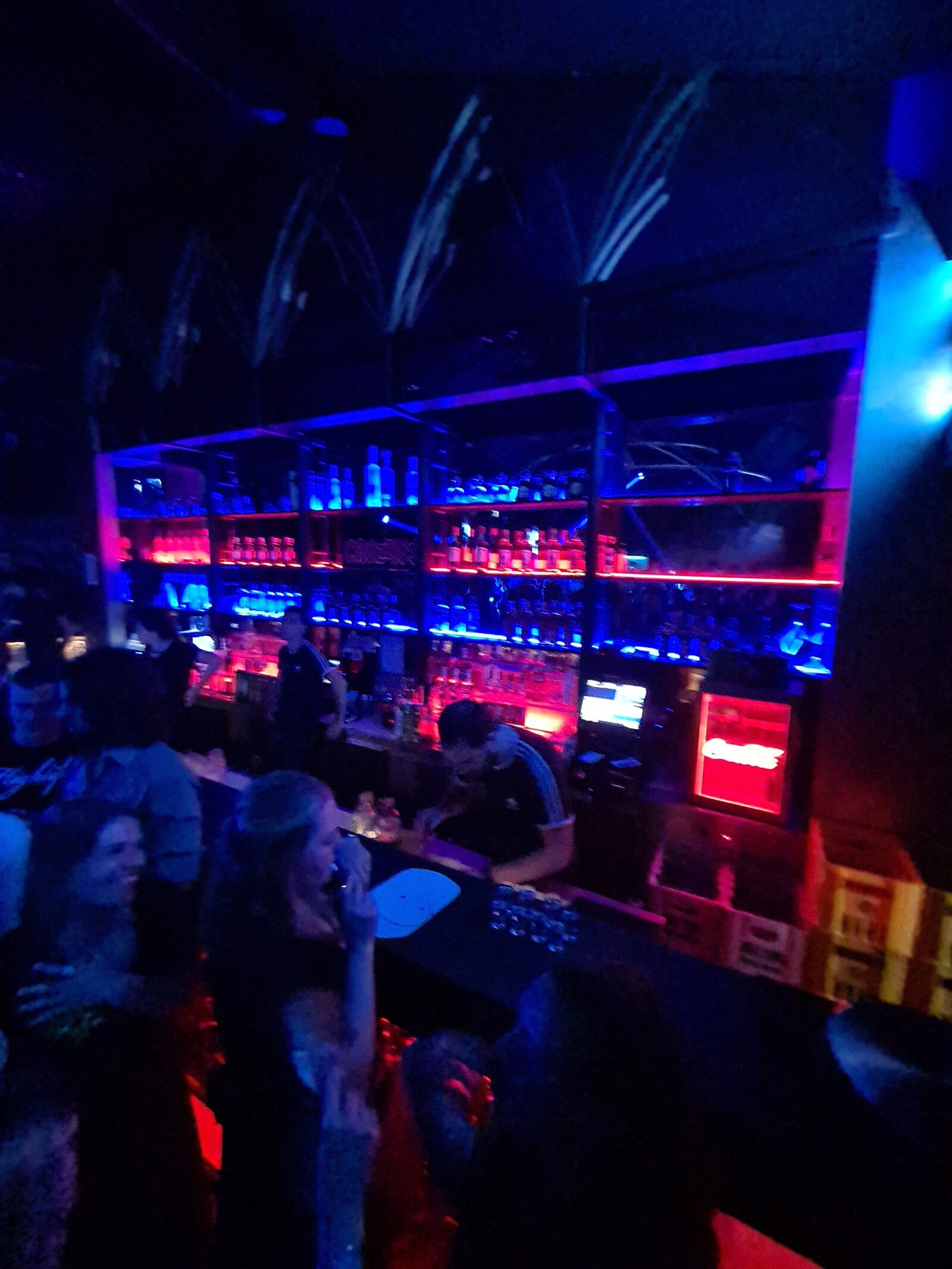 a dark image of a bar in a club with drinks being lined up on the bar