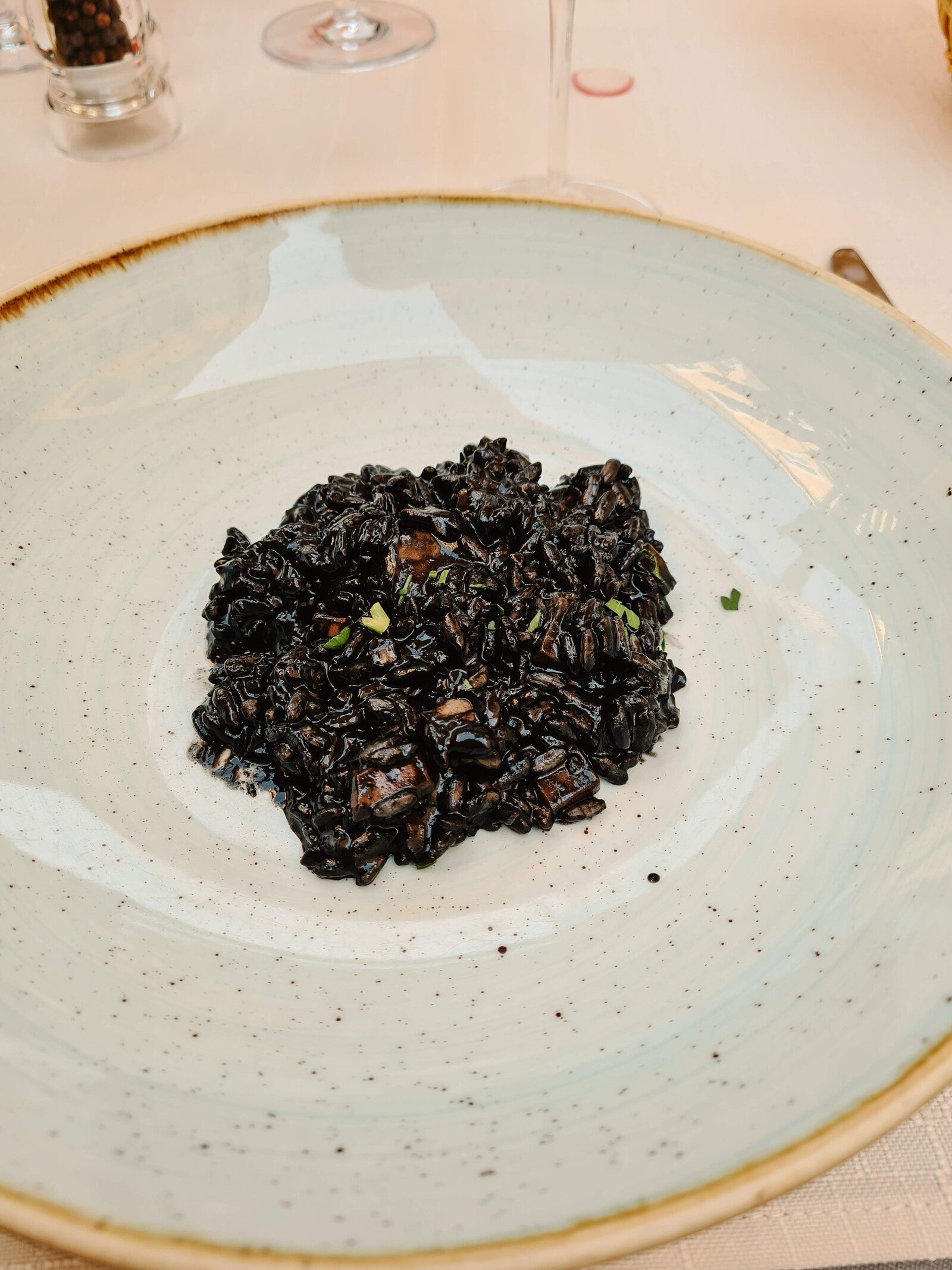 A white bowl with a black coloured risotto