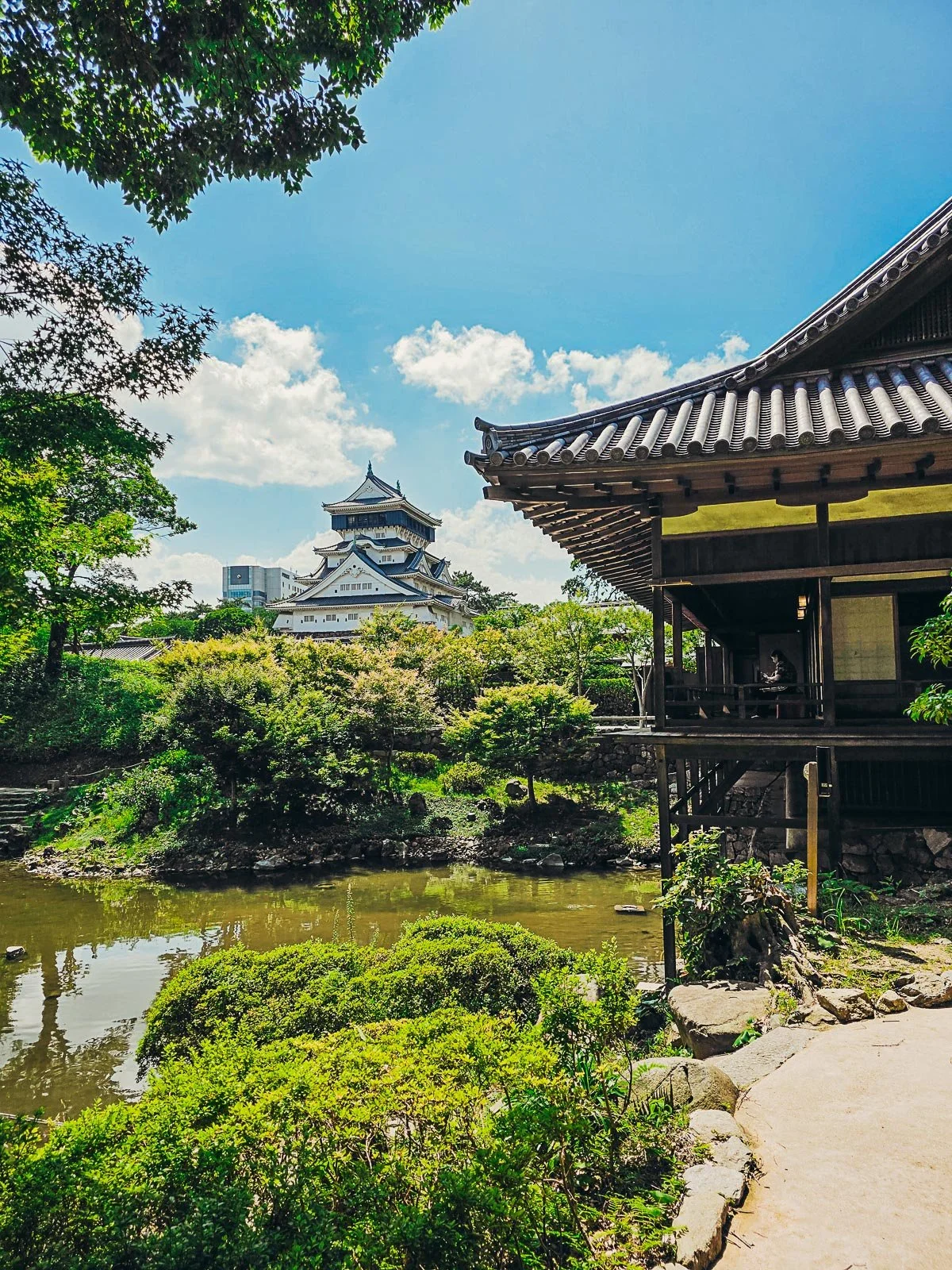 A traditional Japanese garden with a traditional Japanese casytle visible in the distance
