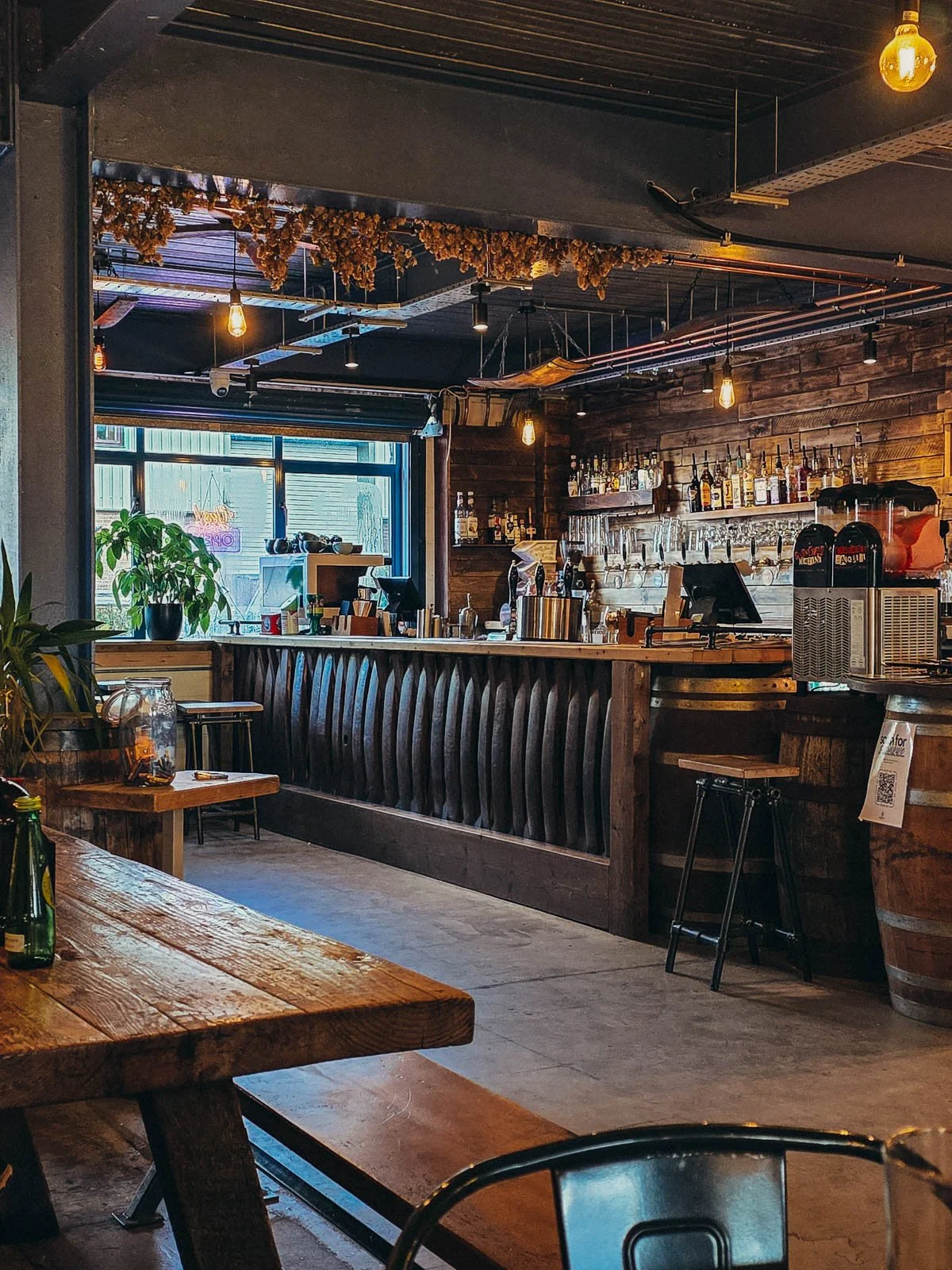 a rustic wooden bar in a brewery with many beer taps on the wall behind