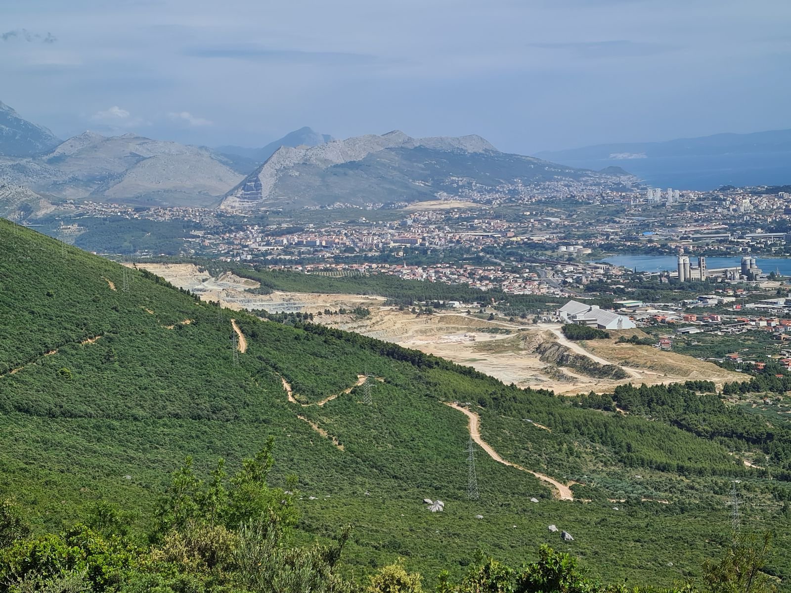 landscape view from a mountain with green slopes and city in the distance