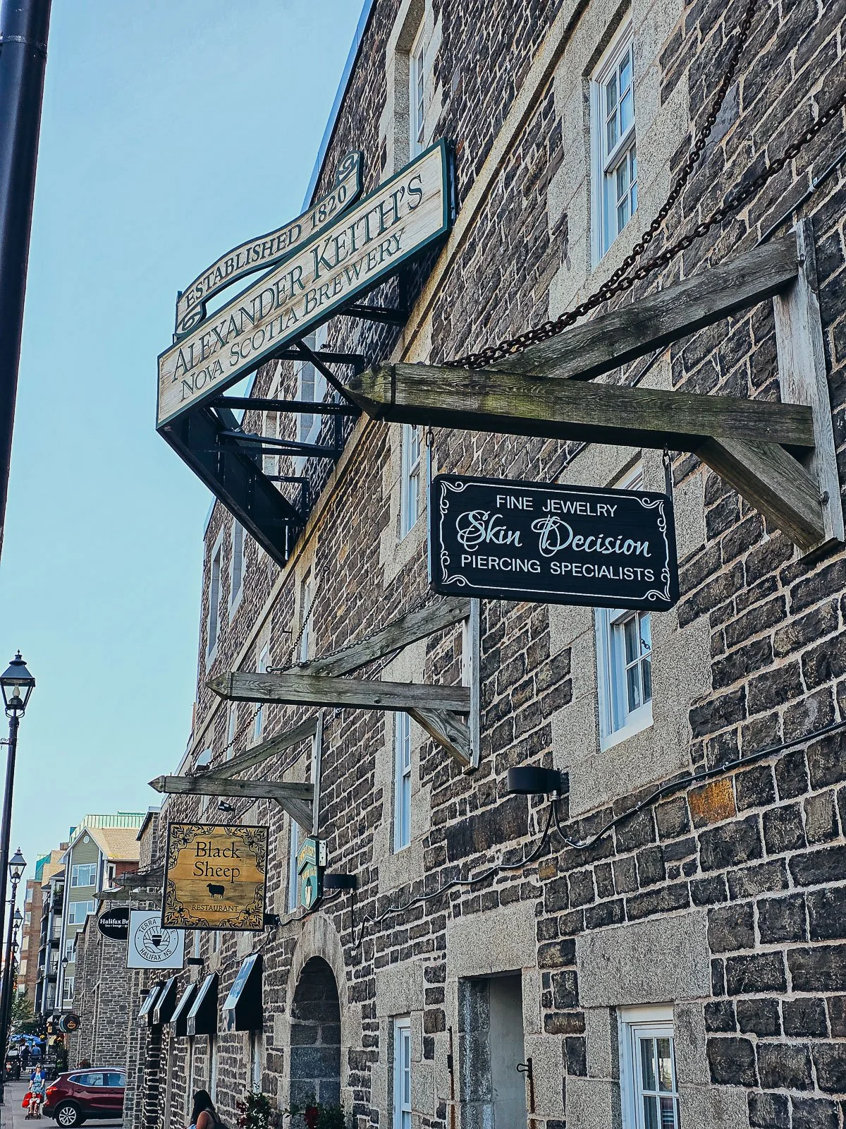 A large old stone brewery with many wooden signs hanging from its exterior