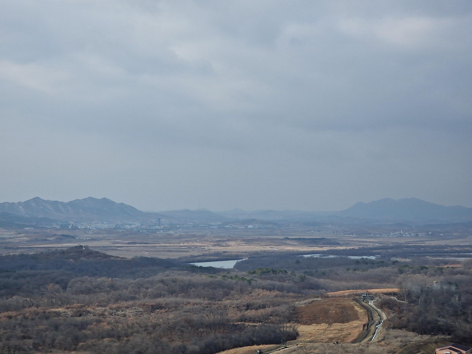 a grey, barren landscape with mountains in the distance