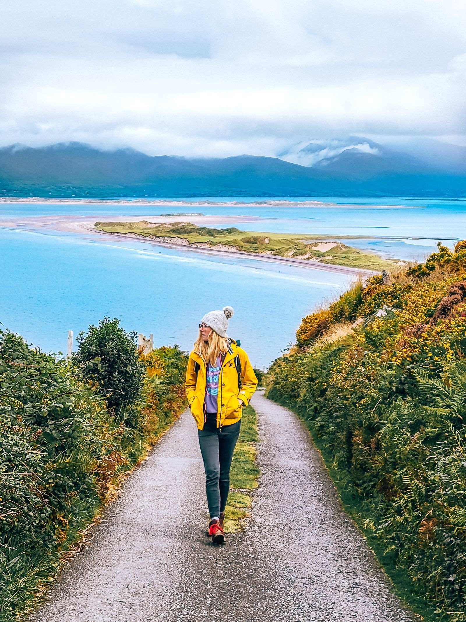 Girl walking down paved Road with the ocean on the background
