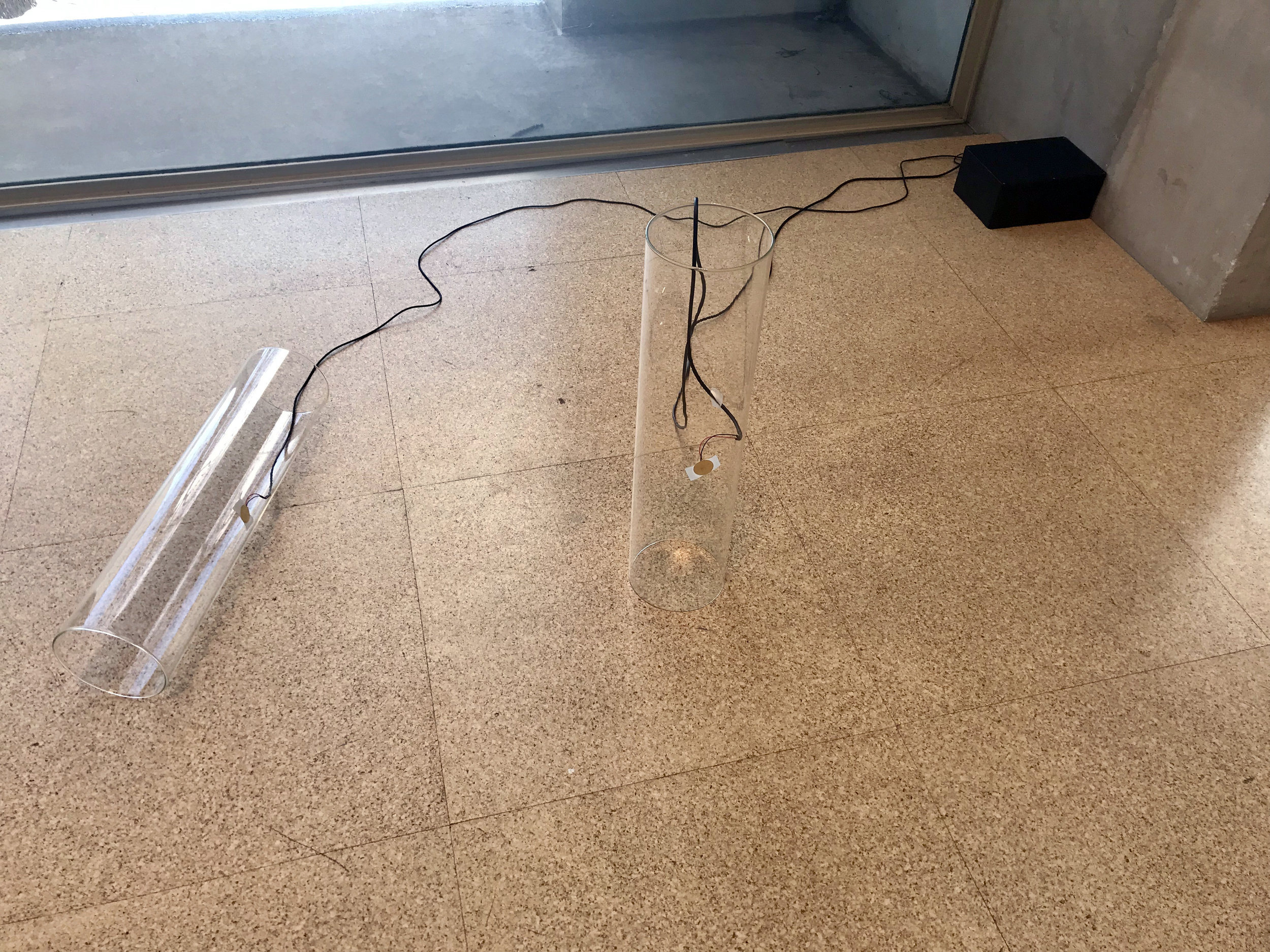 Mary Helena Clark, Ligature (2017). Glass cylinders, piezo discs, audio cable, medical tape, amplifier, media player, project box. 24 x 6 x 6 inches per cylinder. Image: J. Gleisner.