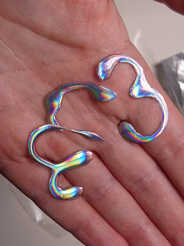 Reusable metallic eyeliner shapes placed on the hand, created for experimenting with face chart designs.