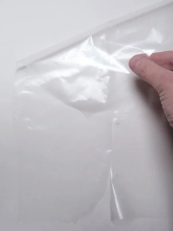 Transparent plastic sheet placed on a flat surface as the first step in creating metallic eyeliner swatches for face charts.